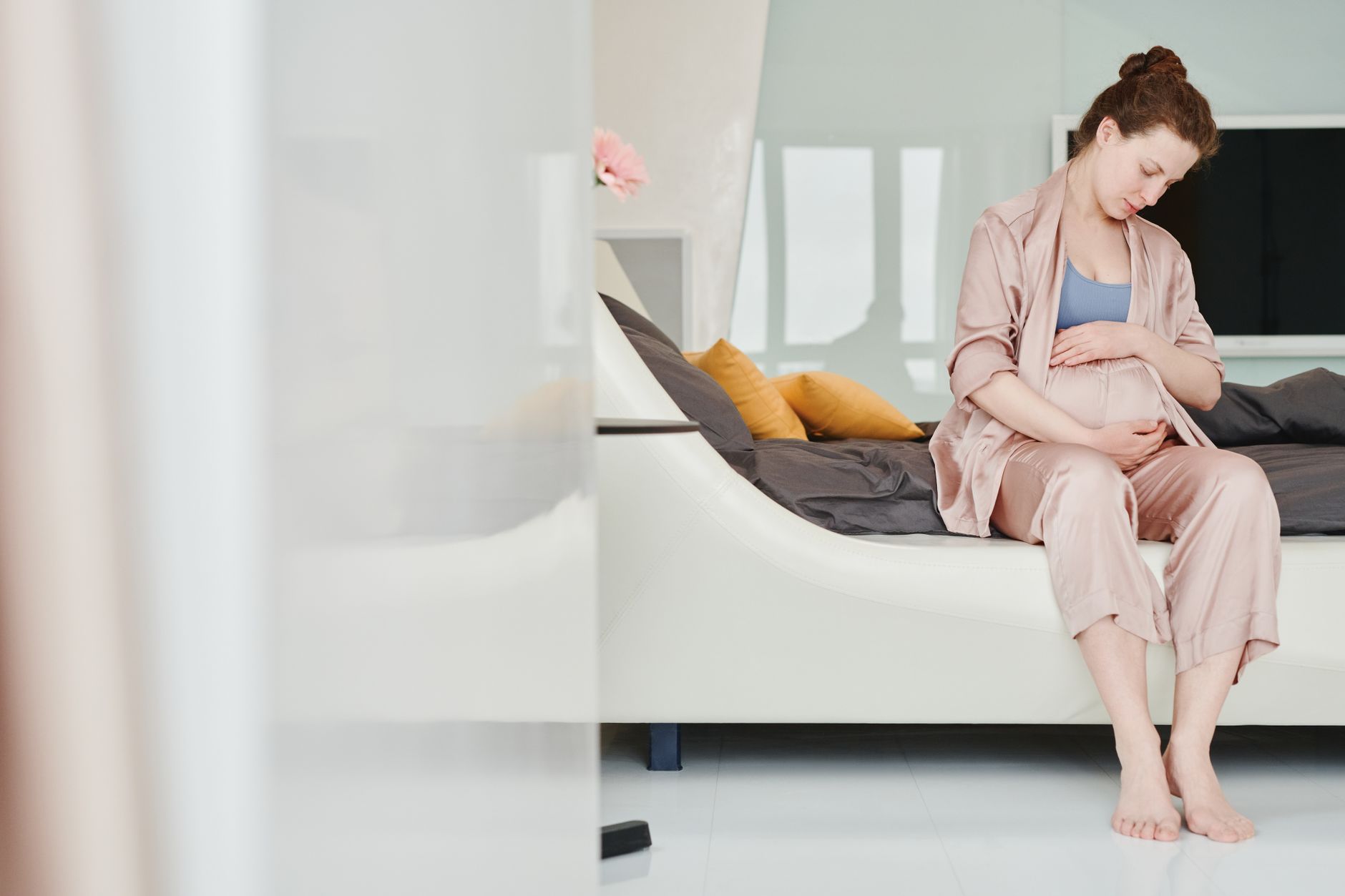 Pregnant woman holding a soft pastel baby blanket, warm morning light, cozy bedroom setting, photorealistic, high detail