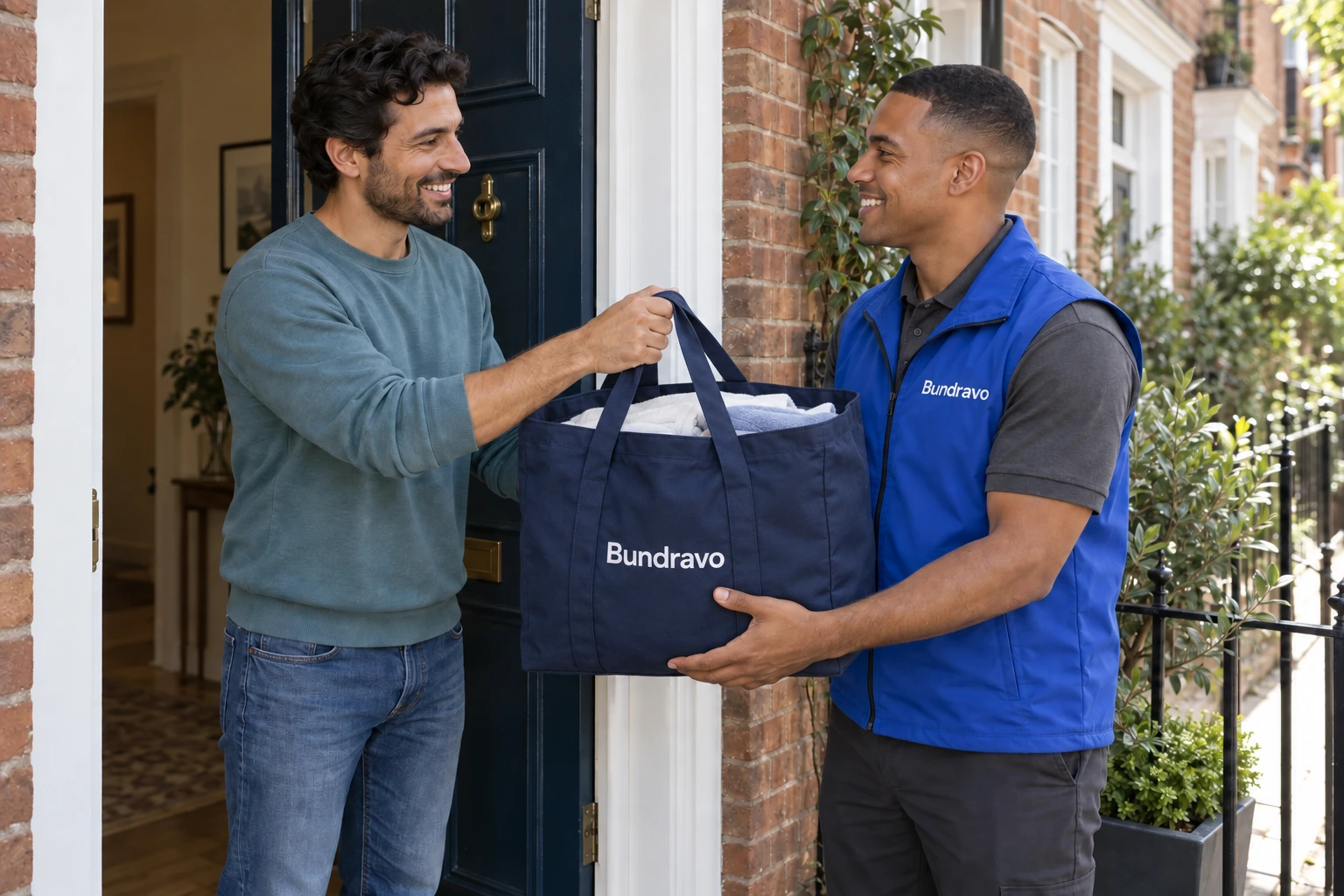A father and Bundravo driver handing over a navy reusable laundry tote at his front door.