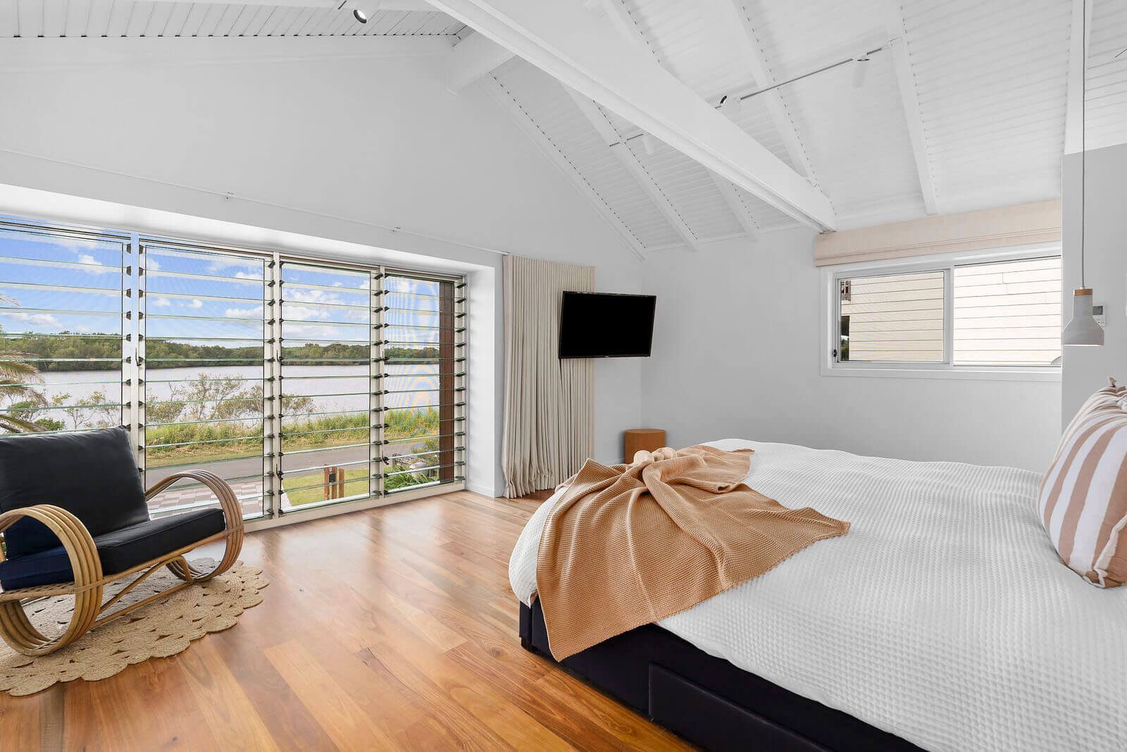 Master bedroom interior showing louvre windows and view towards the lake.