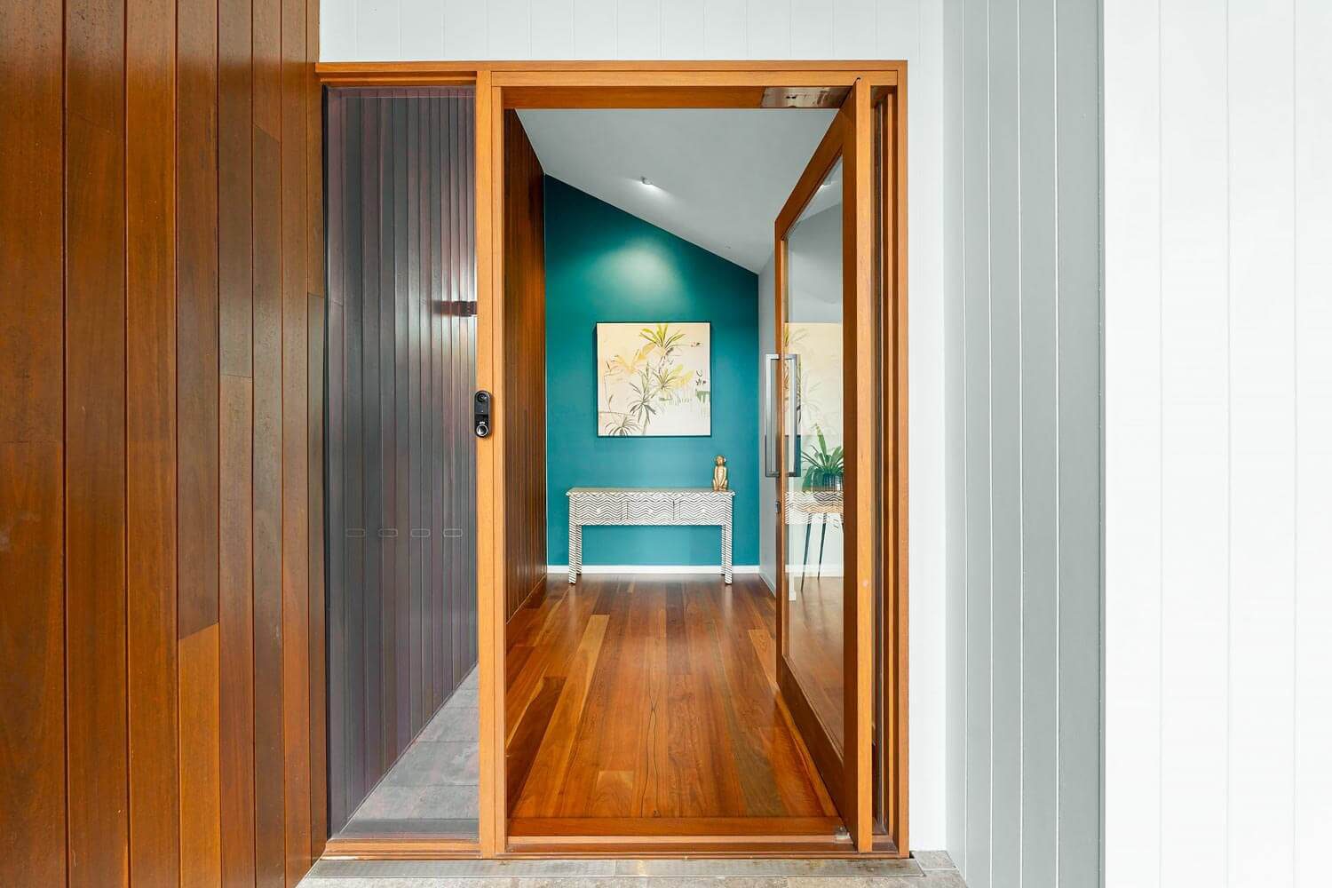 Close up of timber vertical batten screening at the front entrance of a coastal home with a glass front door.