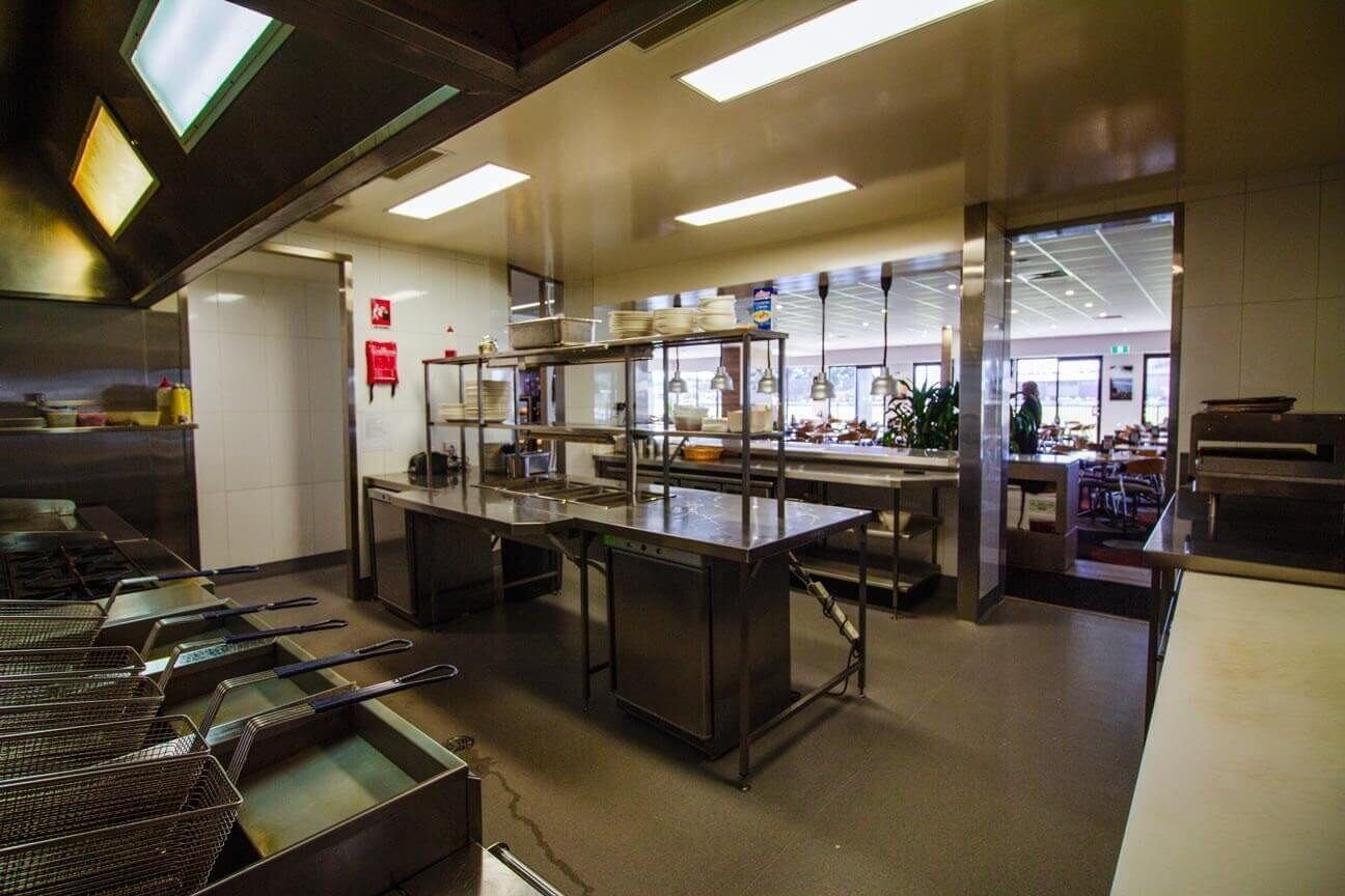 A wide view from the industrial frying station looking towards the service pass and the club dining area.