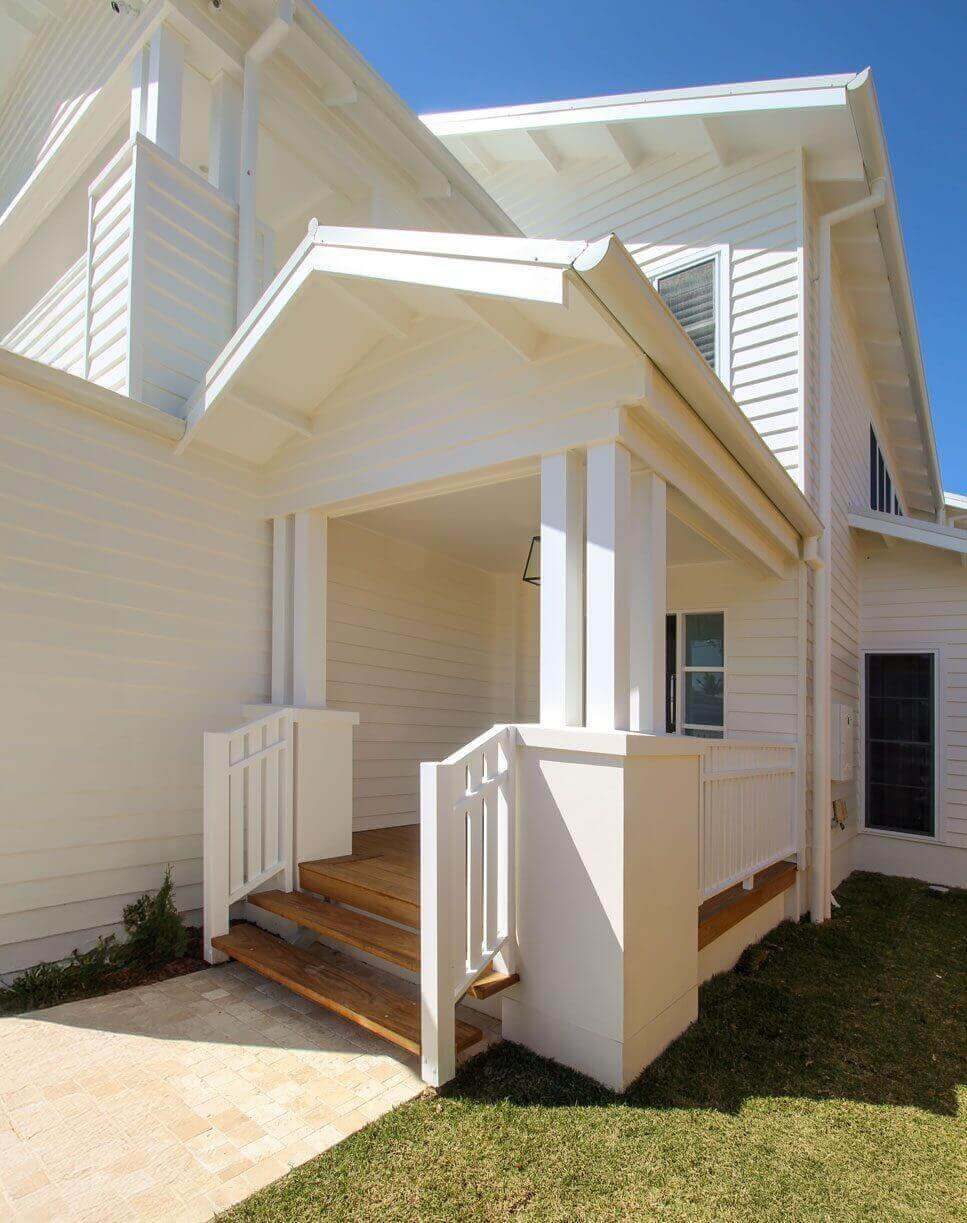 White weatherboard exterior detail with timber stairs and breezeway entrance.