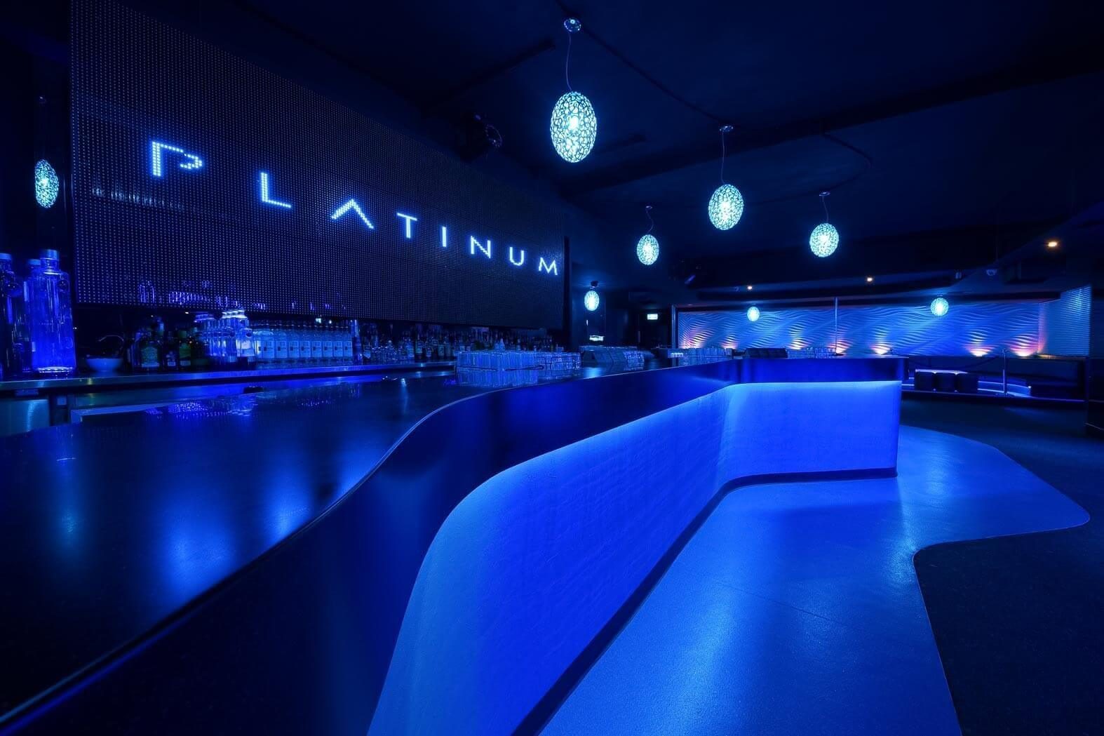 Main bar area featuring integrated blue lighting, patterned pendant fixtures, and a prominent digital signage display.
