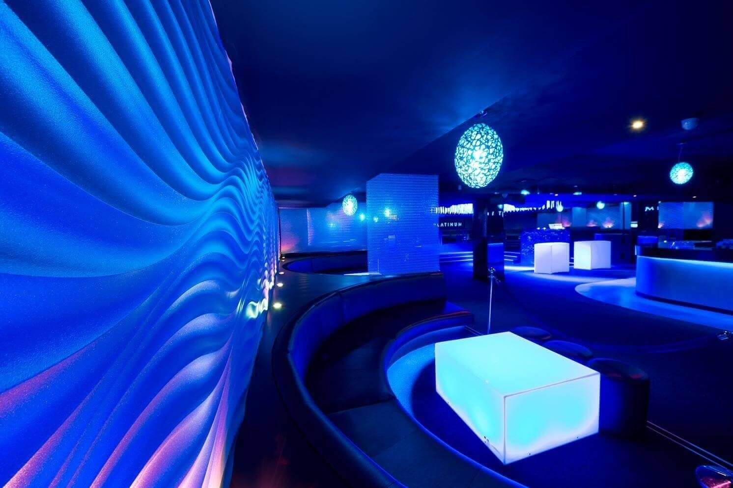Curved booth seating alongside a tactile 3D wall surface illuminated by dynamic blue lighting.