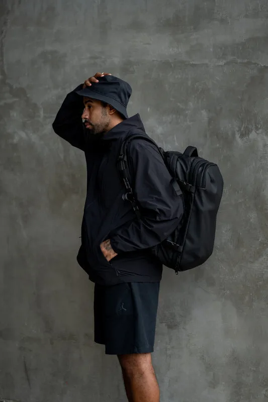 Traveler adjusting the Zephyr Pro shoulder strap against a concrete wall