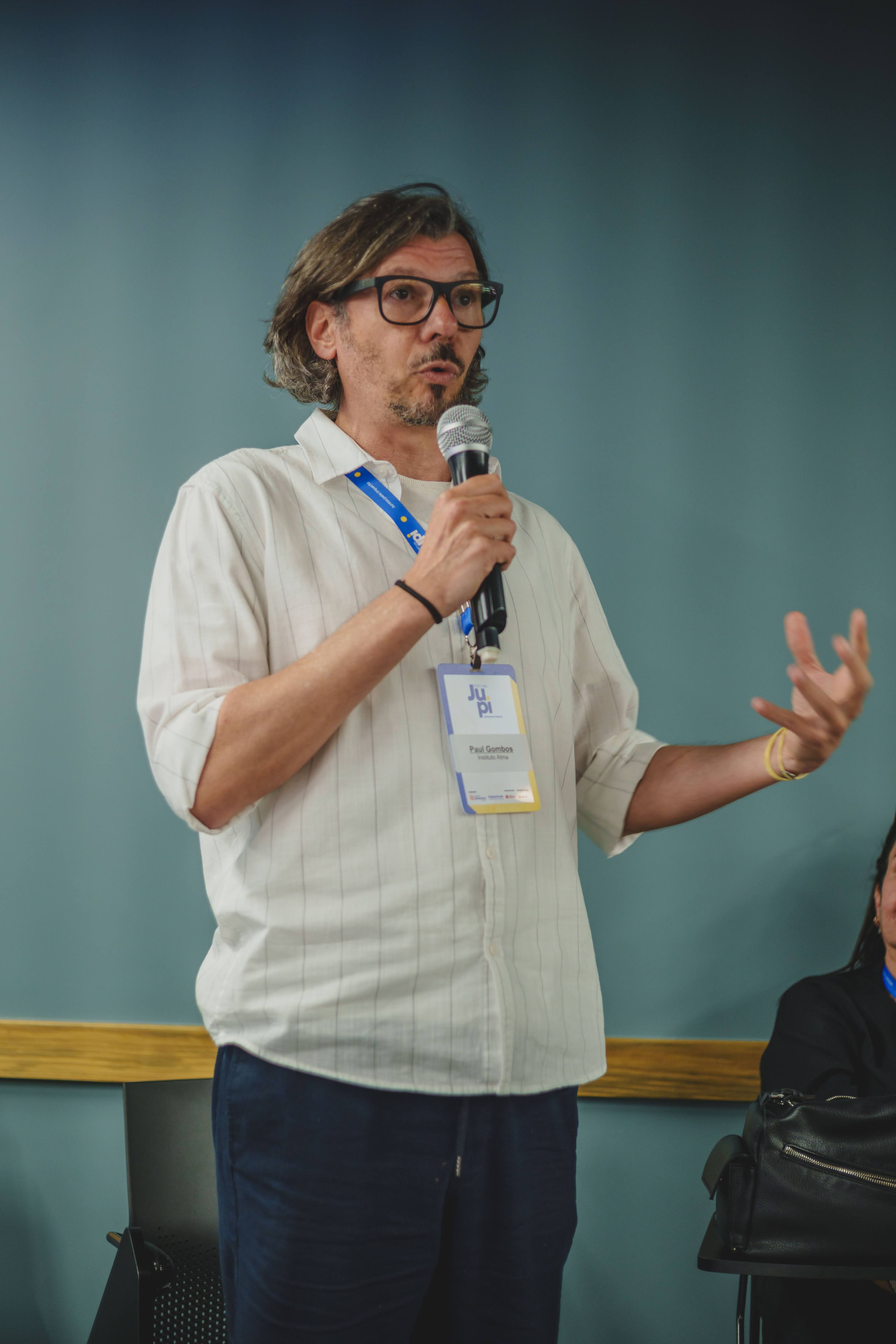 Paul is standing on stage holding a microphone and speaking to an audience during a presentation about authenticity.