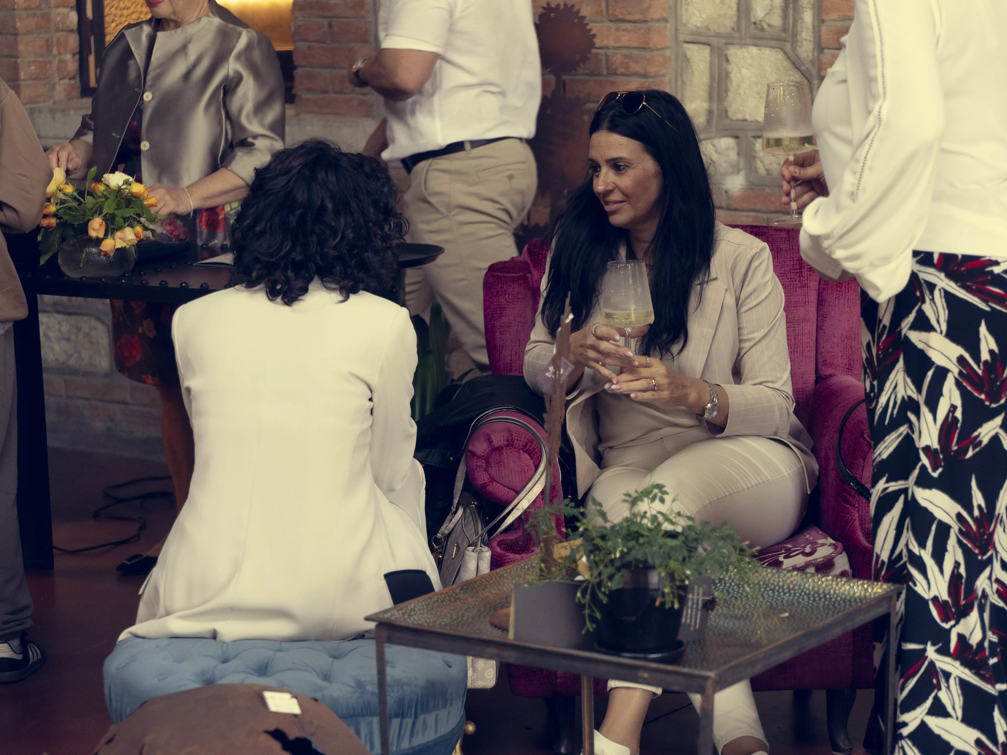 Persone sedute su una poltrona, che bevono vino e chiacchierano.