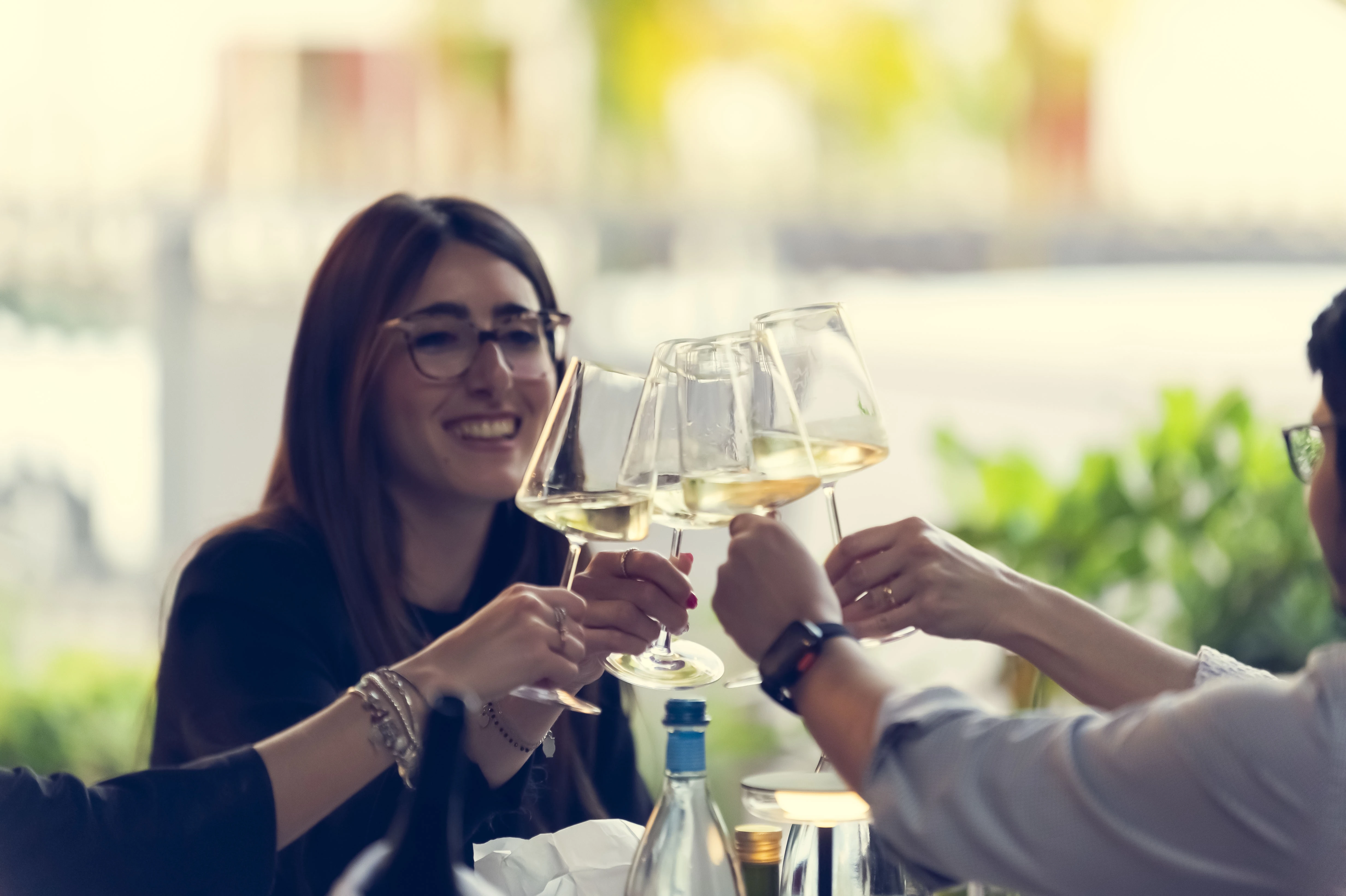 Amici che brindano con calici di vino bianco.