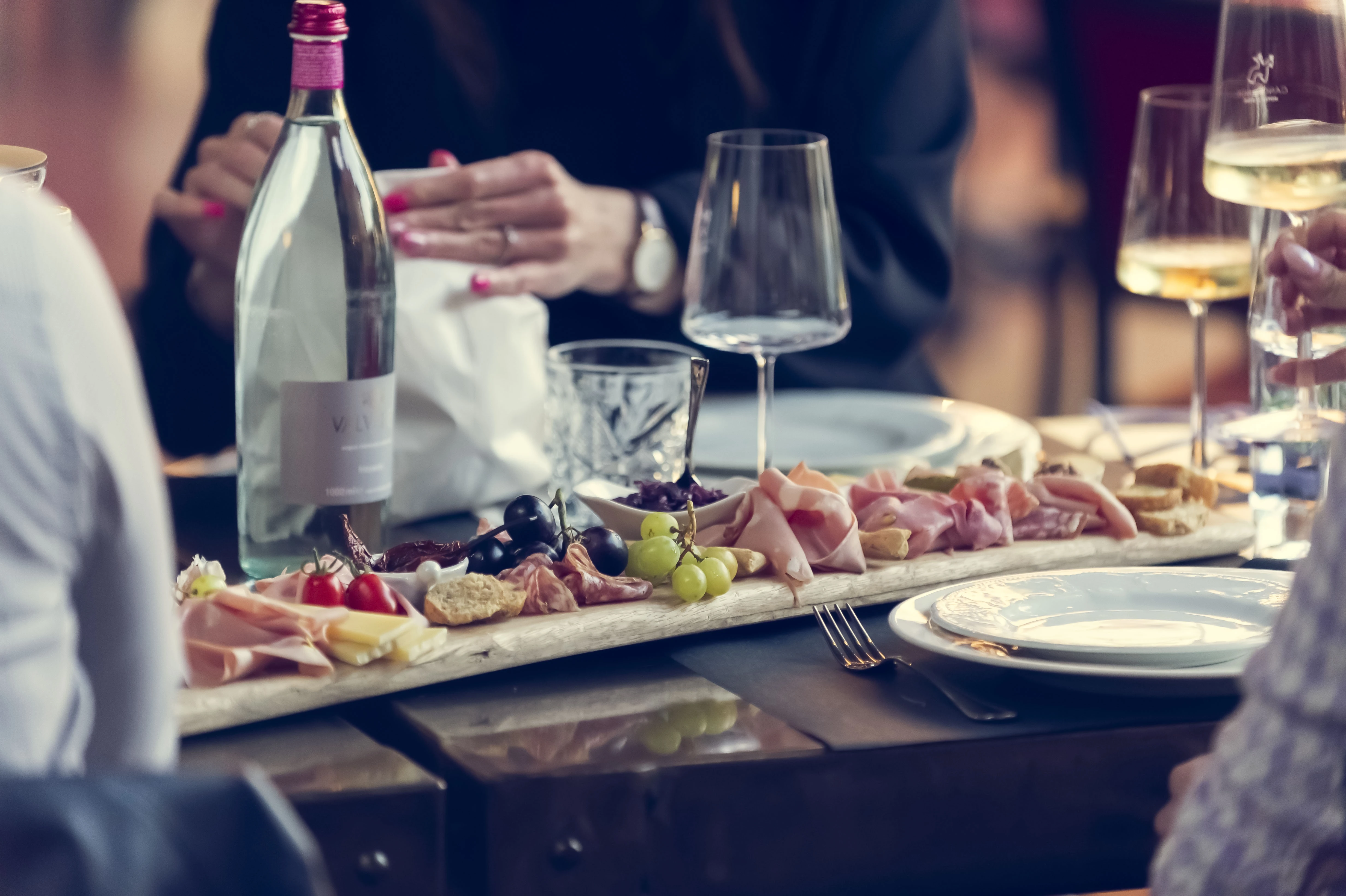 Un tavolo imbandito con salumi, formaggi e frutta, pronto per una cena conviviale.