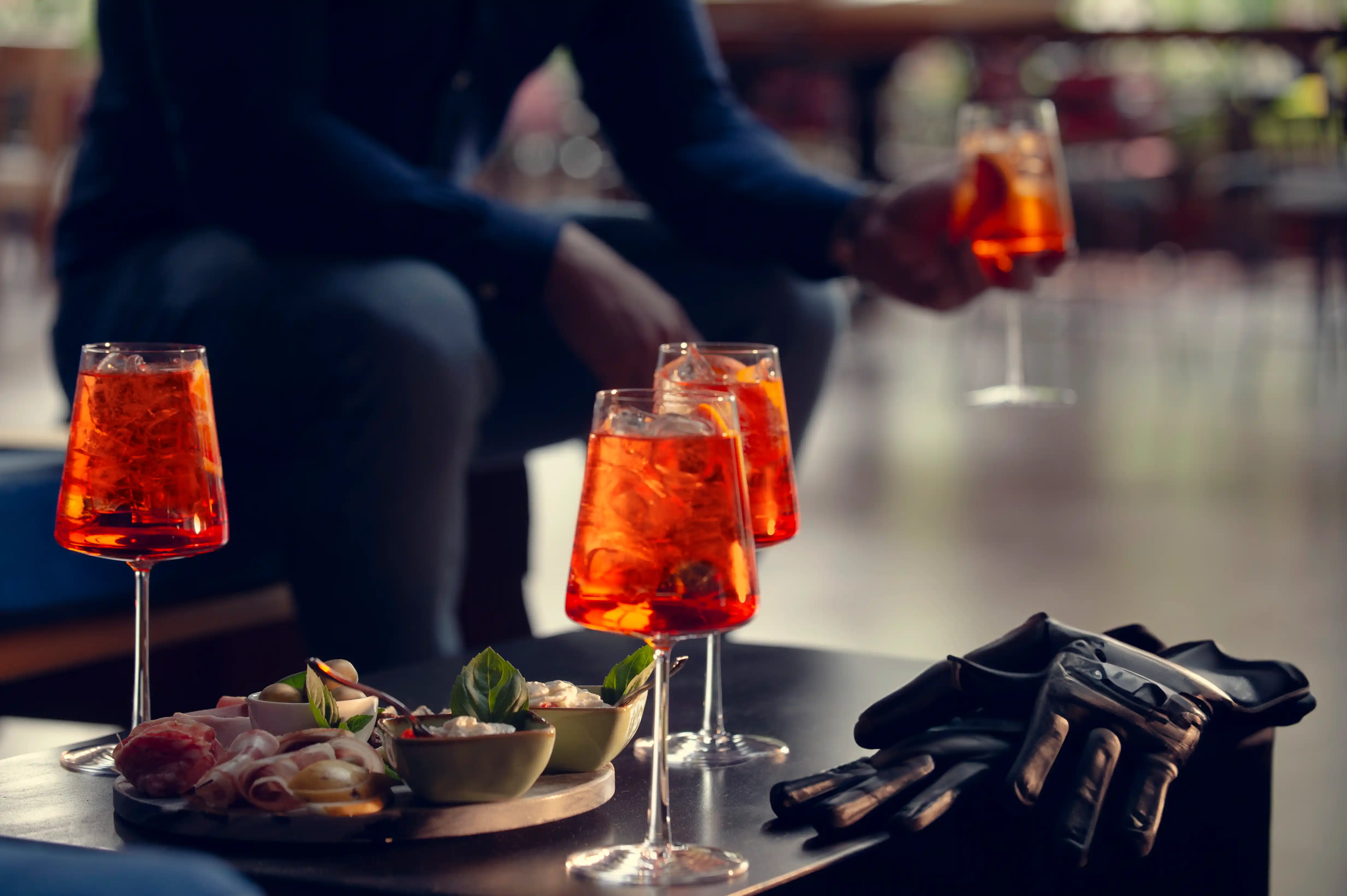 Un aperitivo con stile: Spritz, stuzzichini e guanti in pelle.