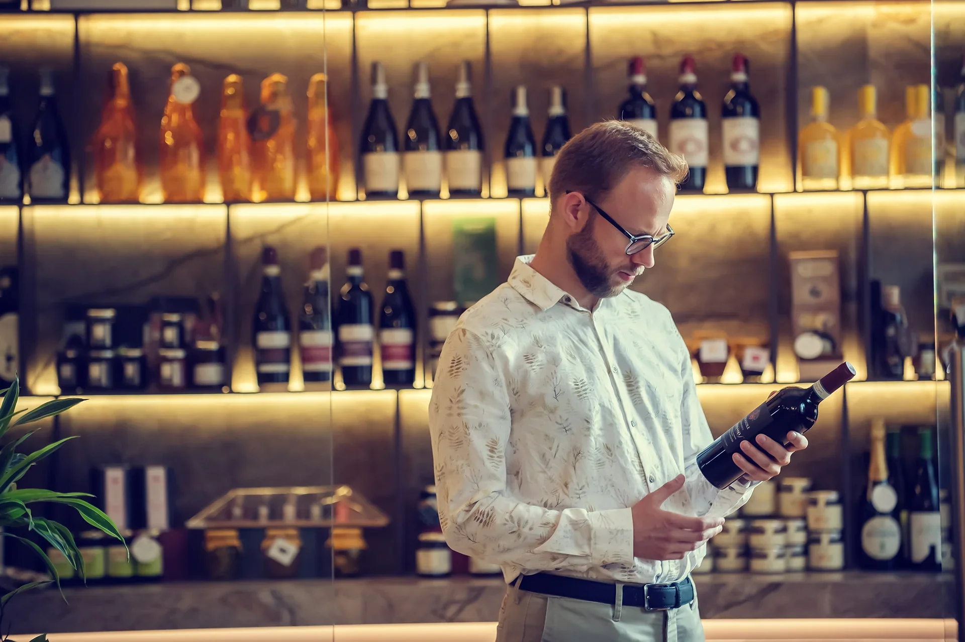 Mann betrachtet Weinflasche in Weinhandlung.