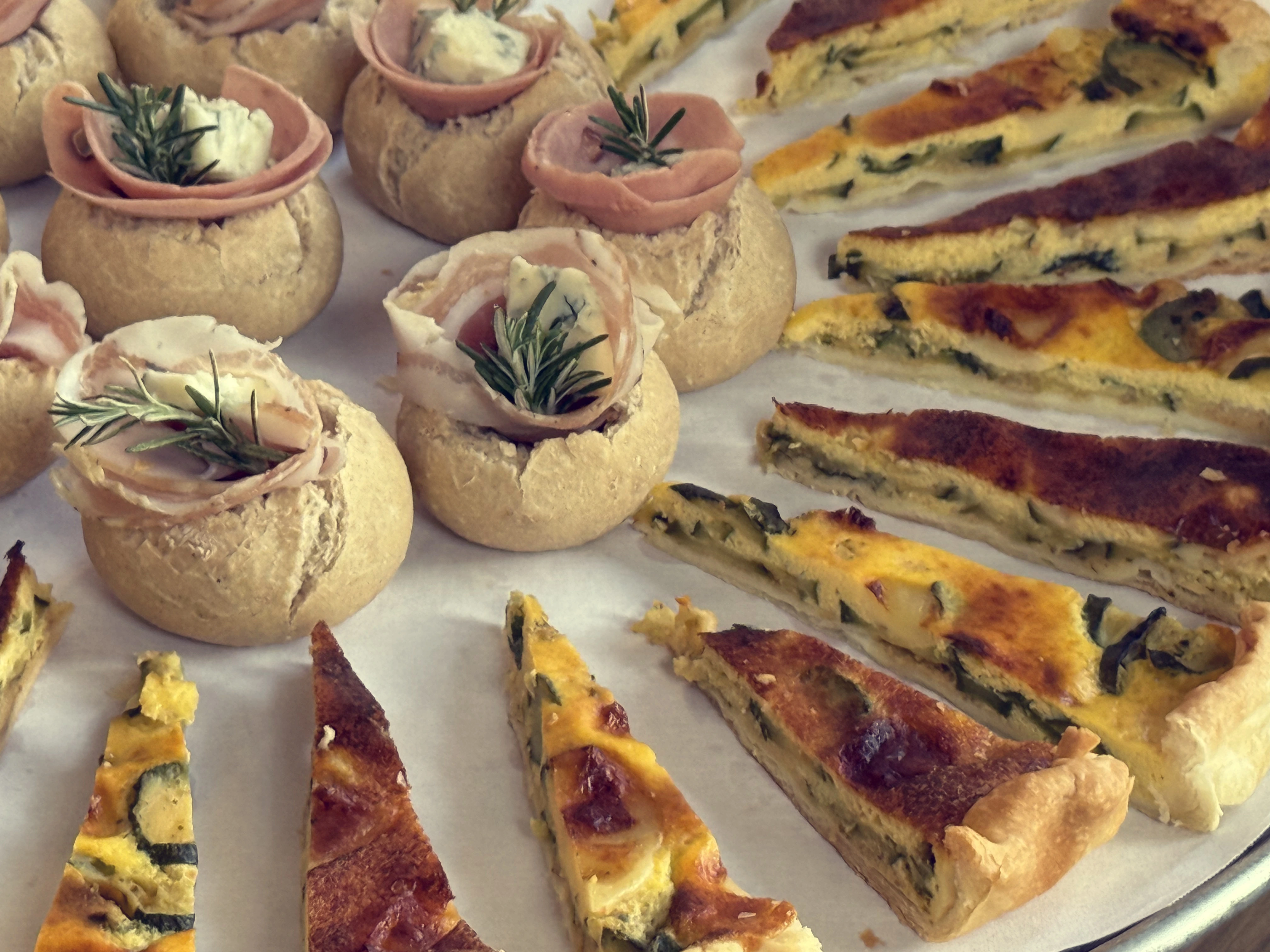 Una selezione di stuzzichini di pane ripieno e fette di torta salata.