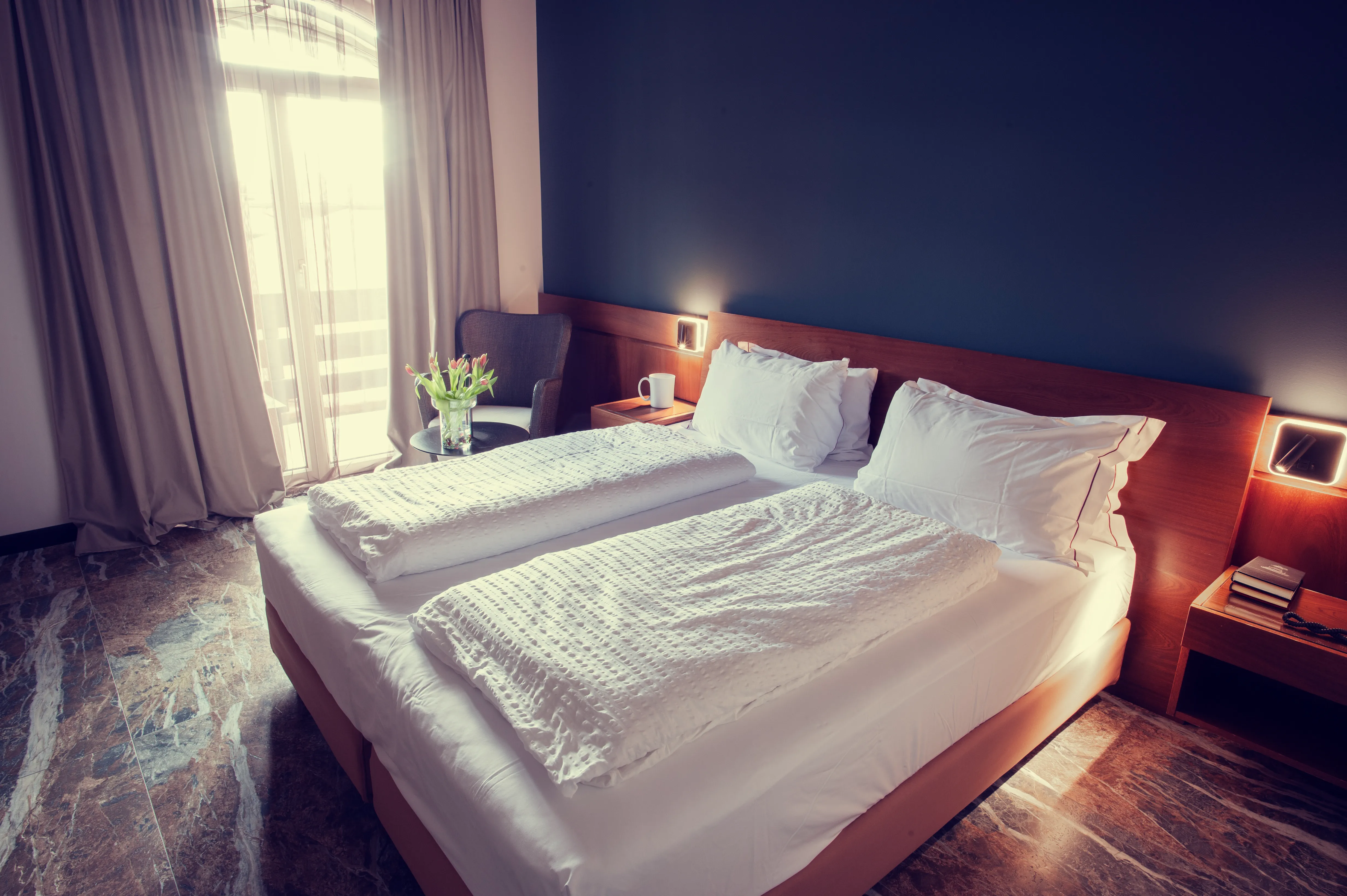 A cozy bedroom with a large bed, a window, and a chair.