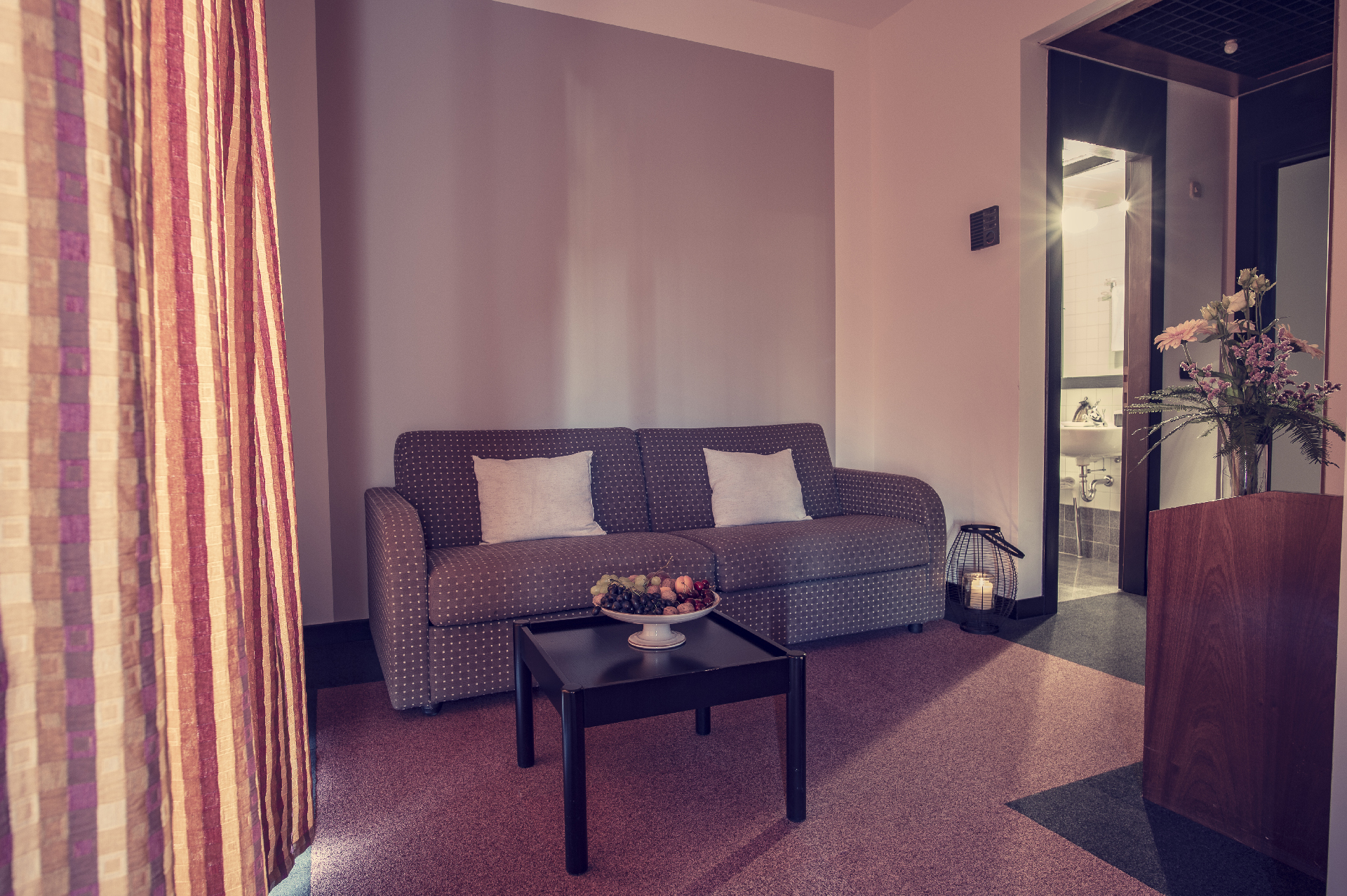 Living room with sofa, coffee table with fruit and fresh flowers.