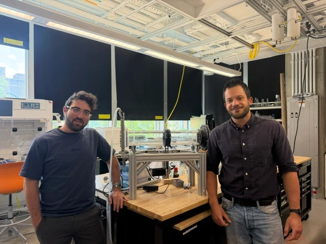 Algae-n-Roll co-founders Dr. David Fierli (right) and Dr. Roberto Capanna (left) pose beside their rotating tank harvester inside the George Washington University's Science and Engineering Hall.