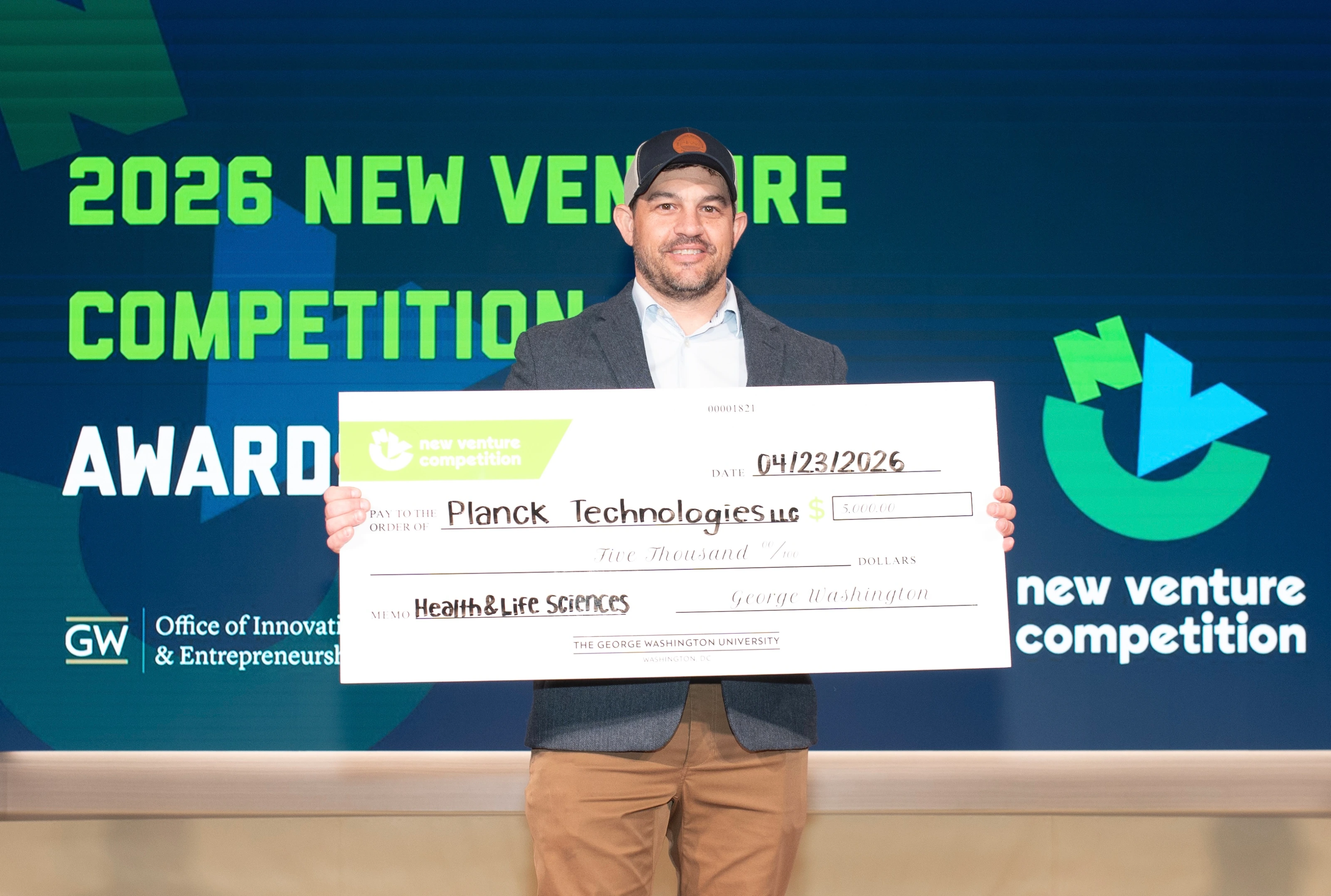Kevin Horrigan holding his check after receiving third place in the Healthcare and Life Sciences Track at GW's New Venture Competition.