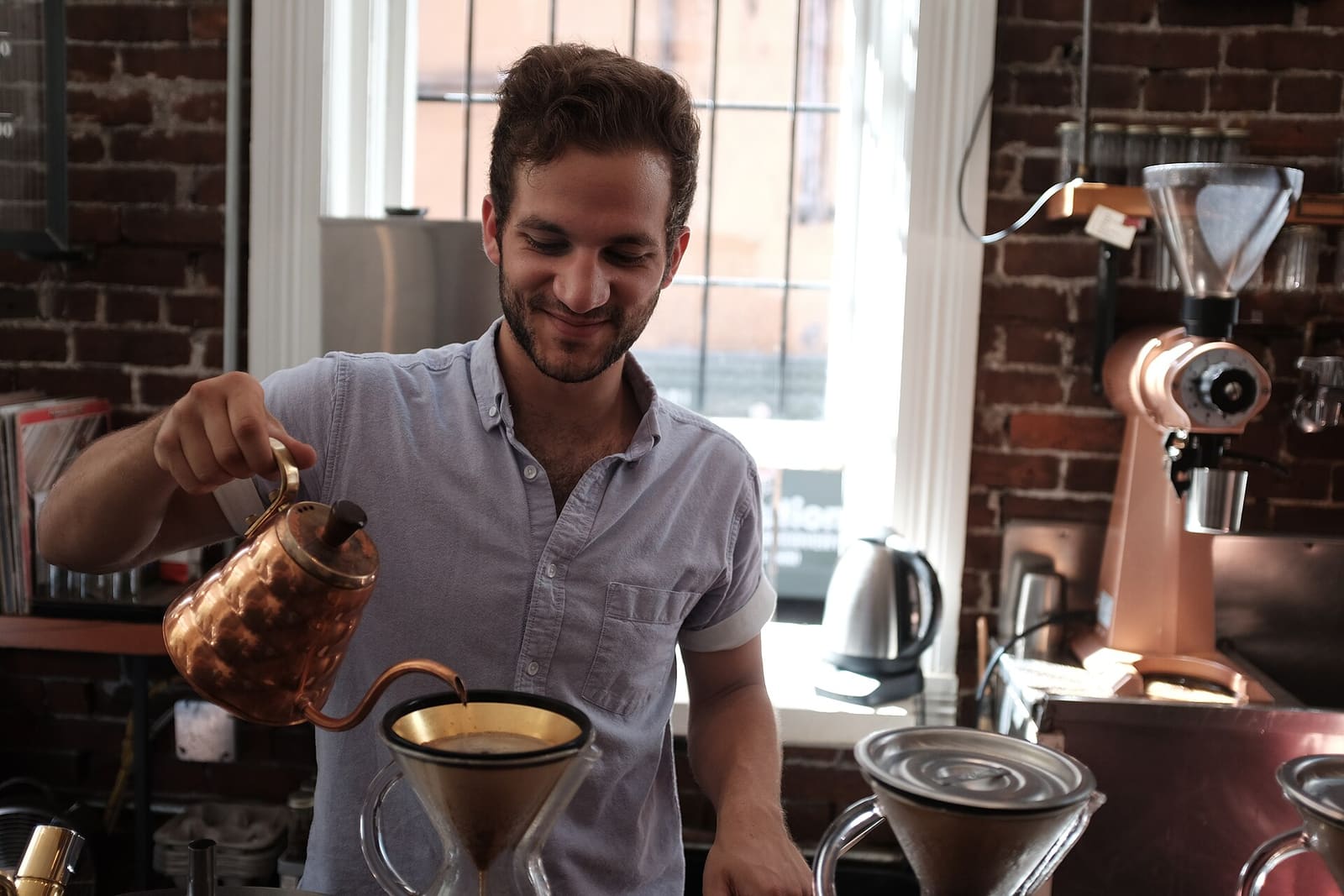 Barista brewing filter coffee with a copper kettle