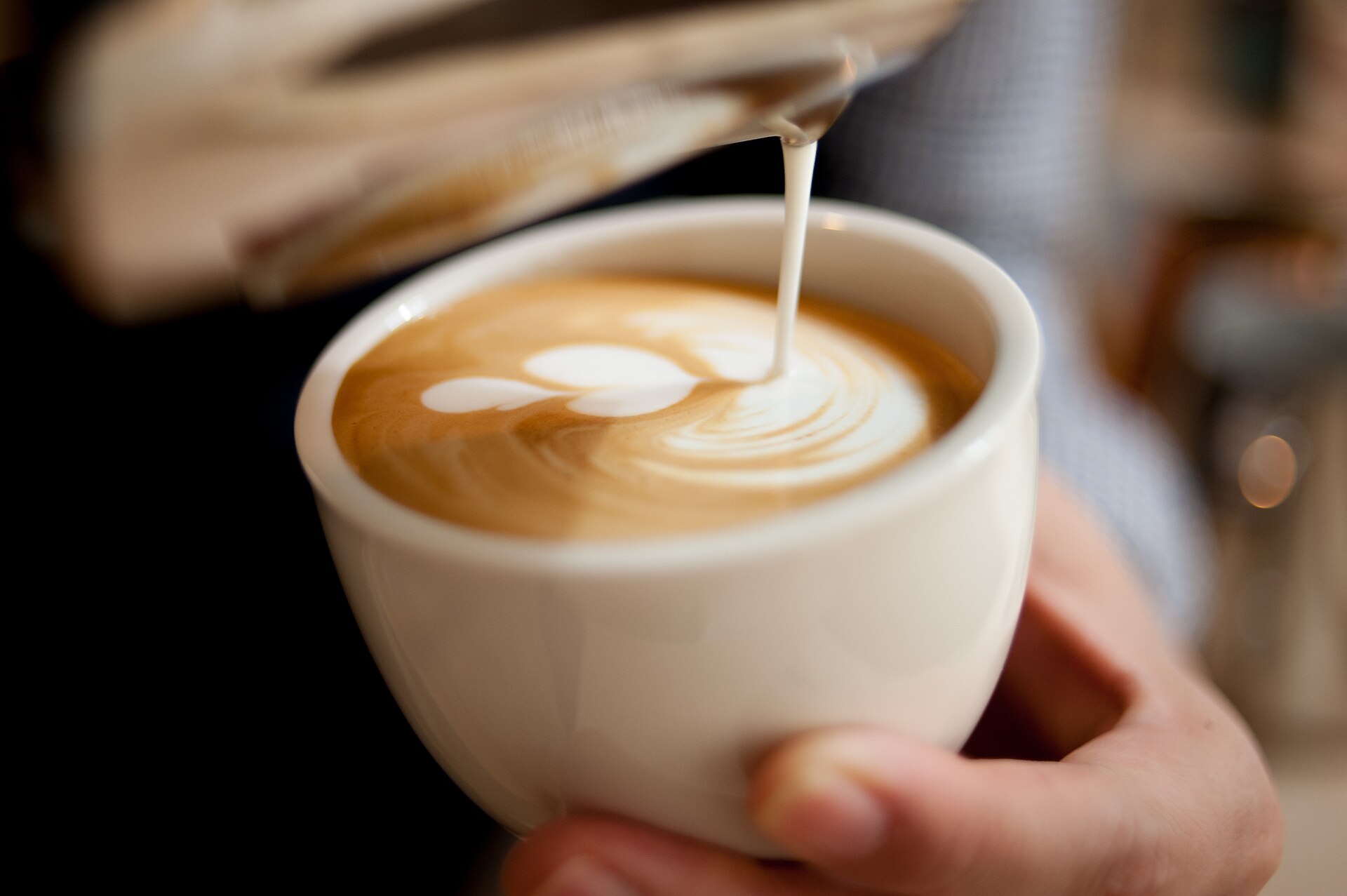 Latte art being poured into a white cup