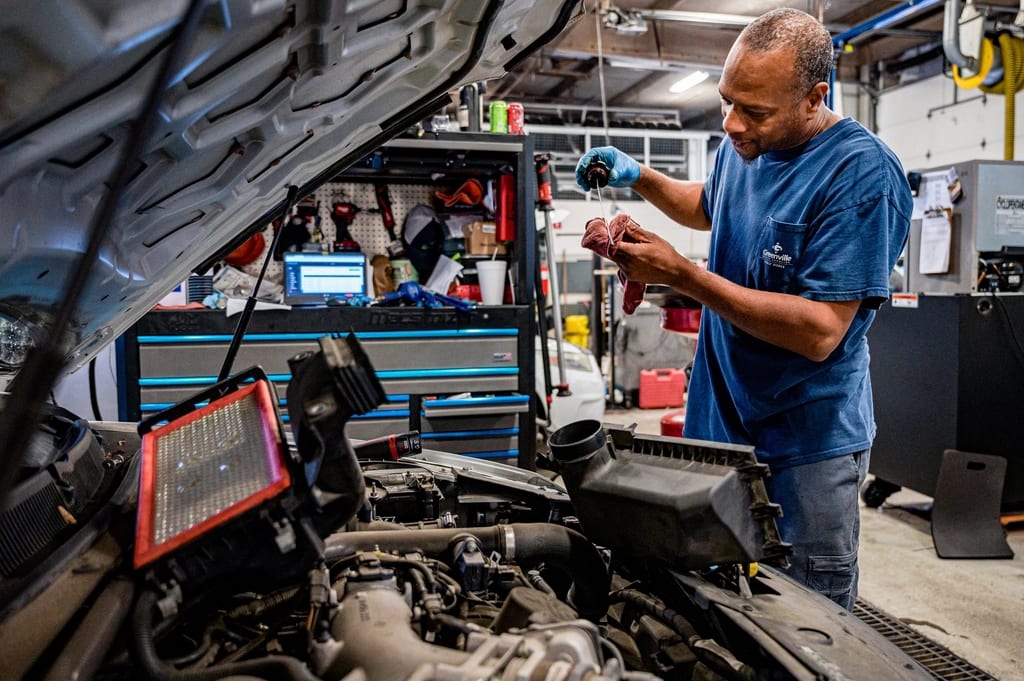 Mechanic checking the oil level under an open hood