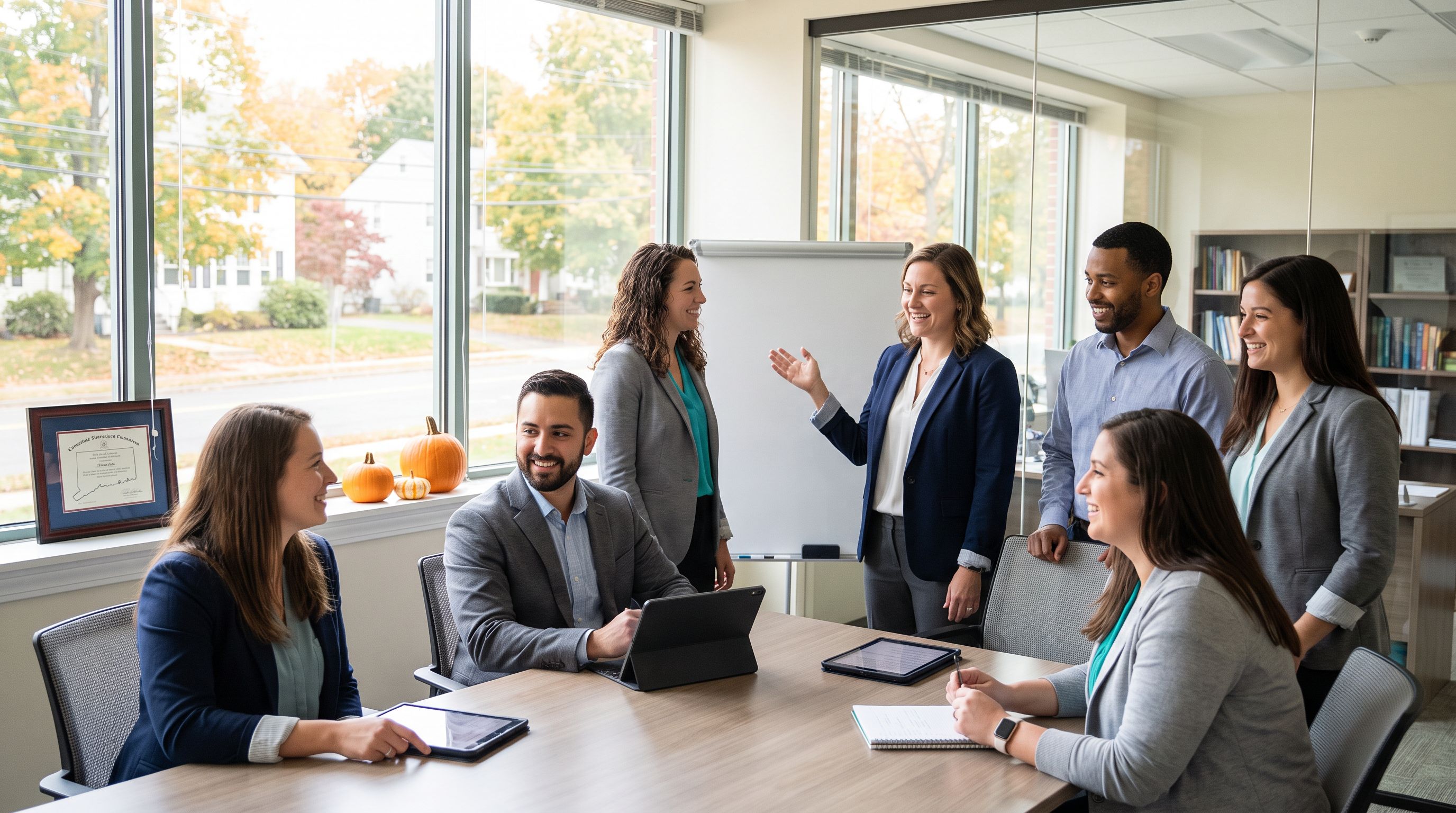 A diverse team of ABA therapy professionals collaborating in a bright, modern Connecticut clinic office with autumn light through the windows