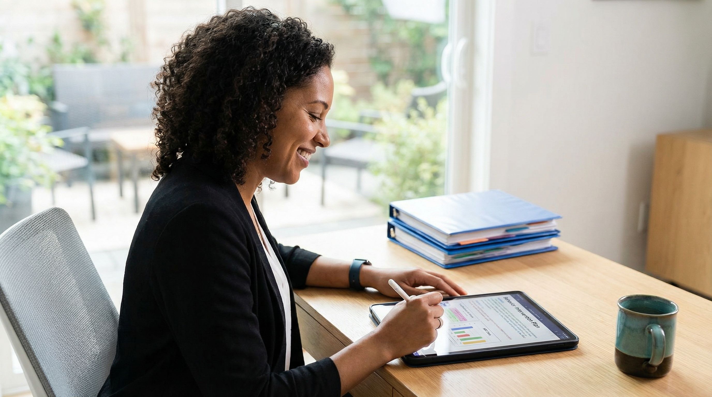 Behavior analyst writing a behavior intervention plan at a modern clinic desk with data charts and tracking graphs