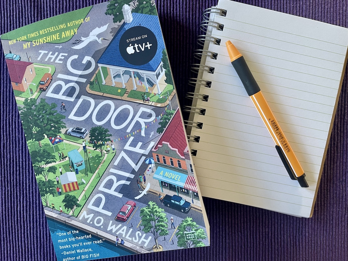 A book lying on a table next to a notebook and pen
