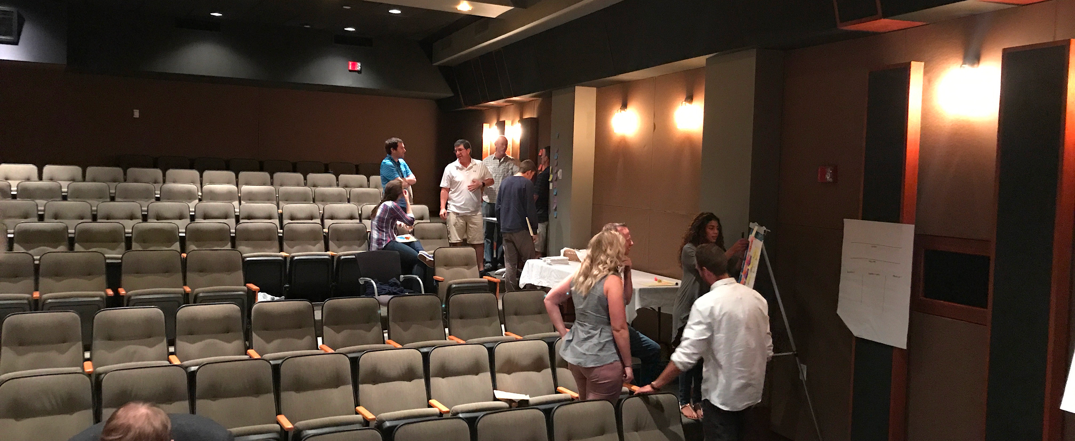 NFL Media workshop participants collaborate in small groups inside a theater-style screening room.