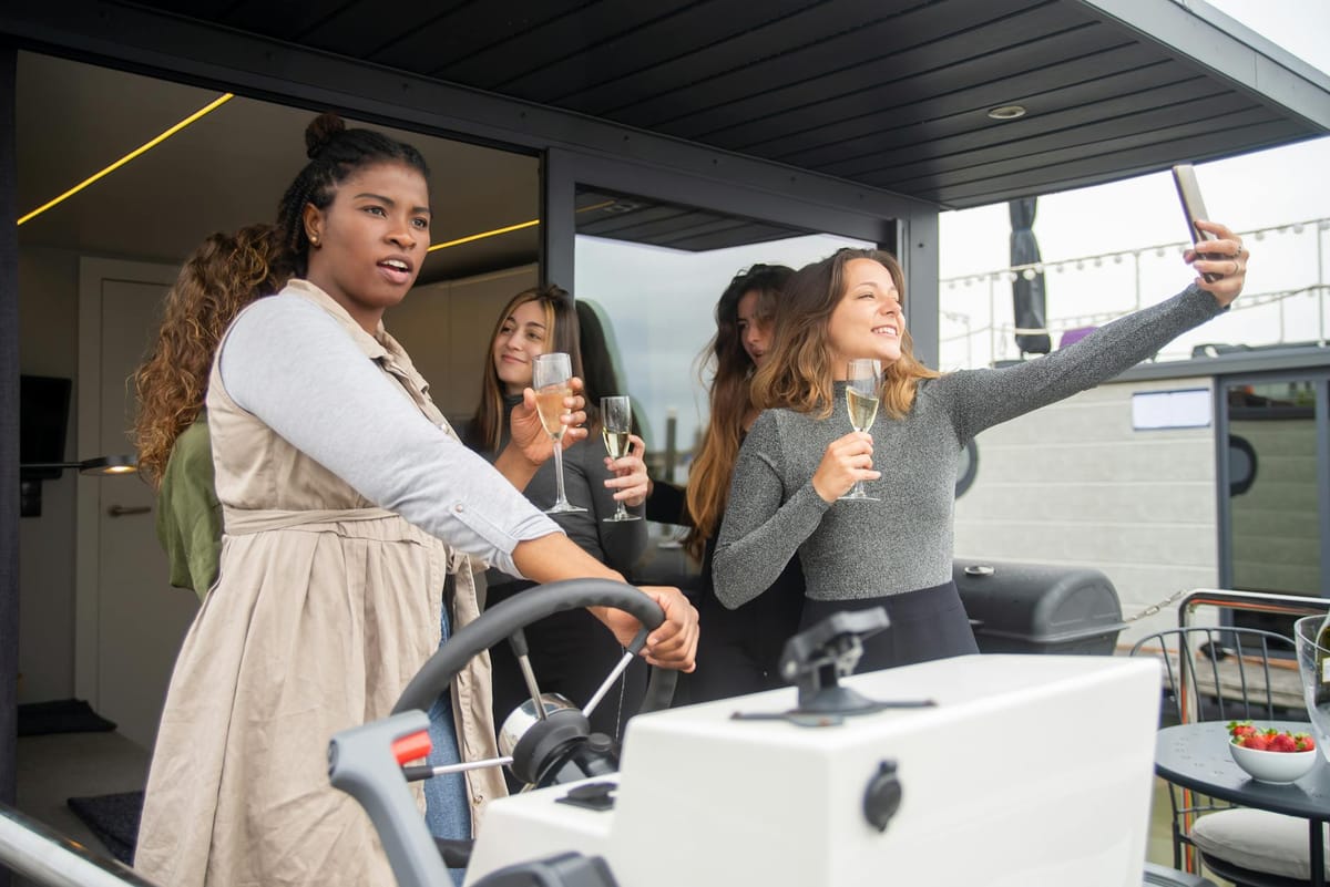 A group of friends reviewing a split-payment screen on a smartphone while seated on a charter boat deck.