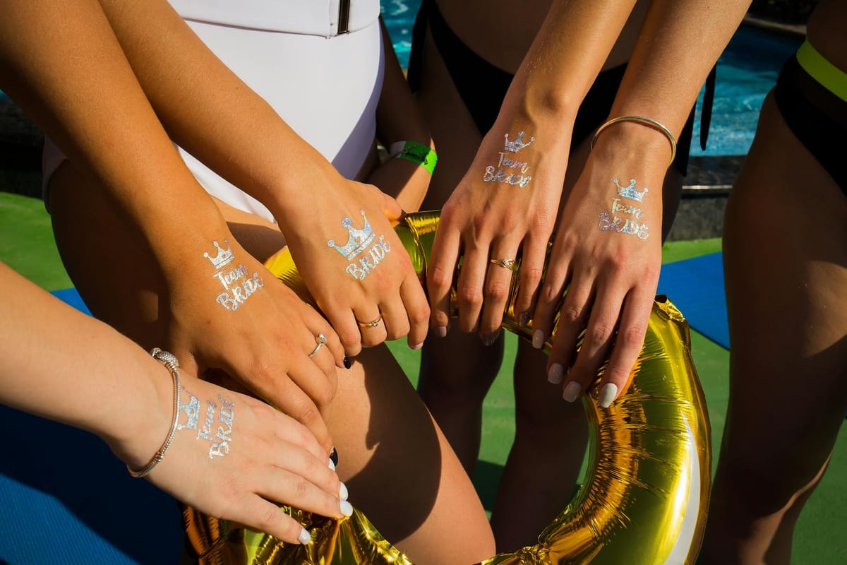 A group of women celebrating a bachelorette party on a yacht deck at sunset.