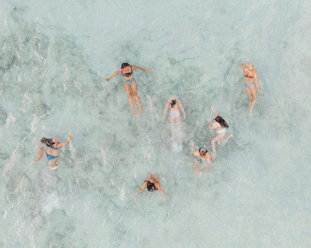 A group of women swimming and floating near a yacht anchored at a Miami sandbar.