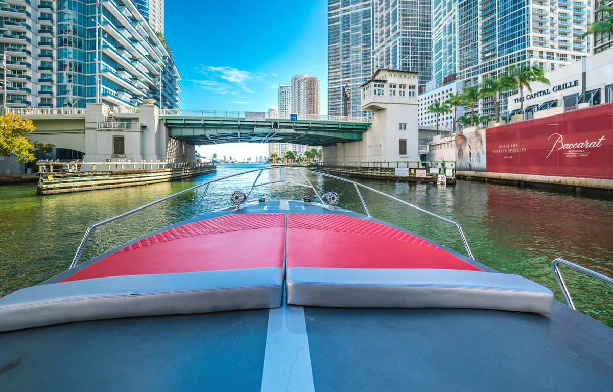 A motor yacht leaves a Brickell marina with the Miami skyline in the background on a clear morning.
