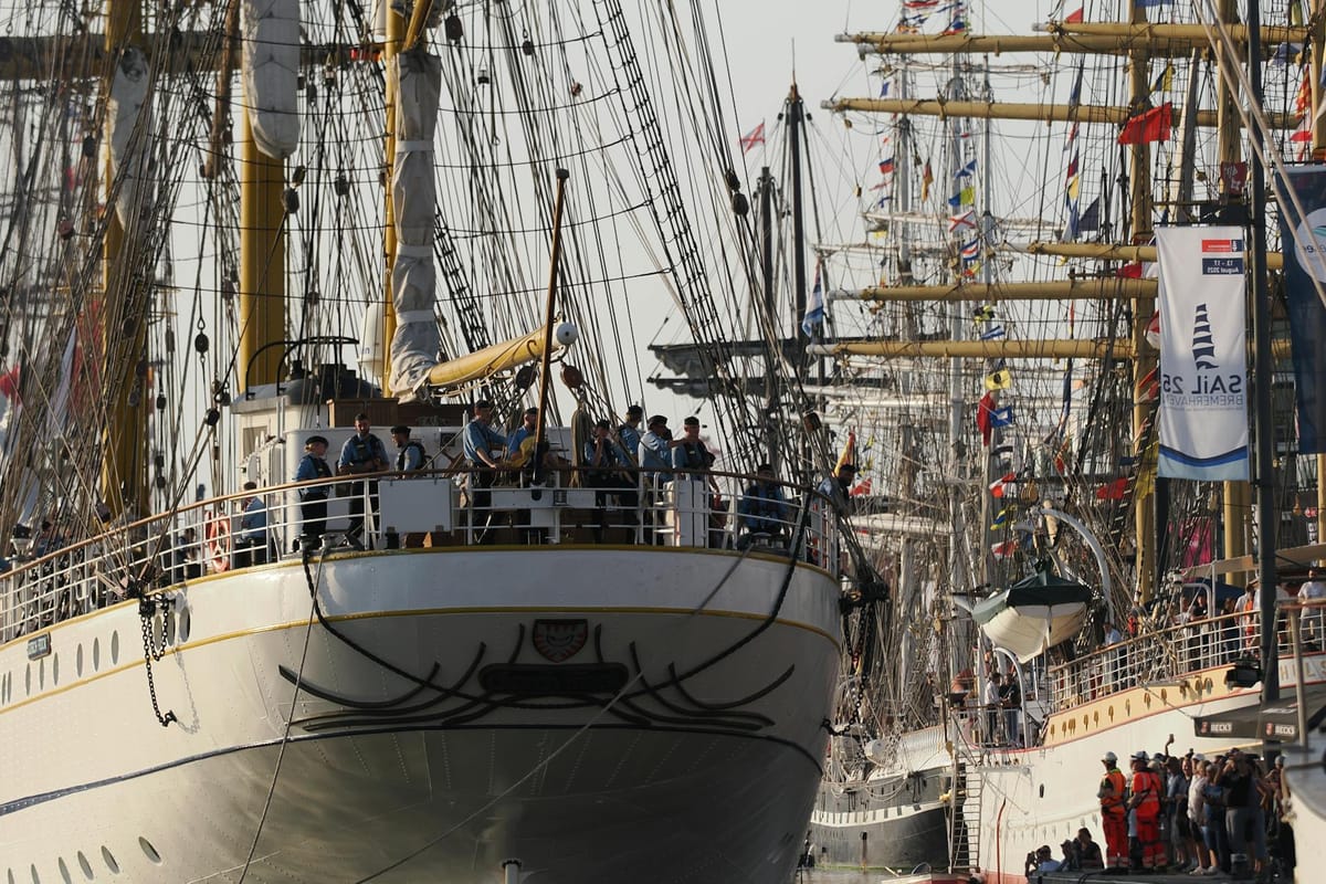 Tall ships moored in Boston Harbor during a summer maritime festival with crowds on the waterfront.