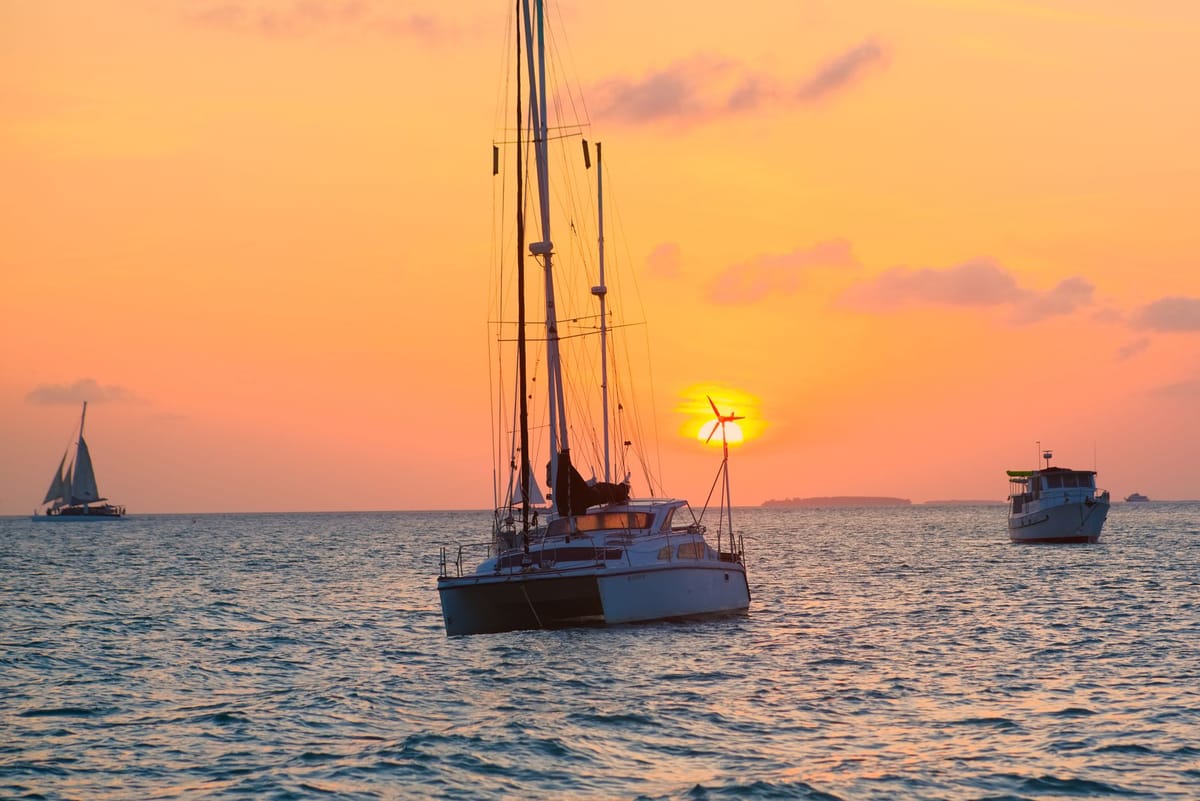 A private yacht anchored in calm turquoise water near the Florida Keys at sunset.
