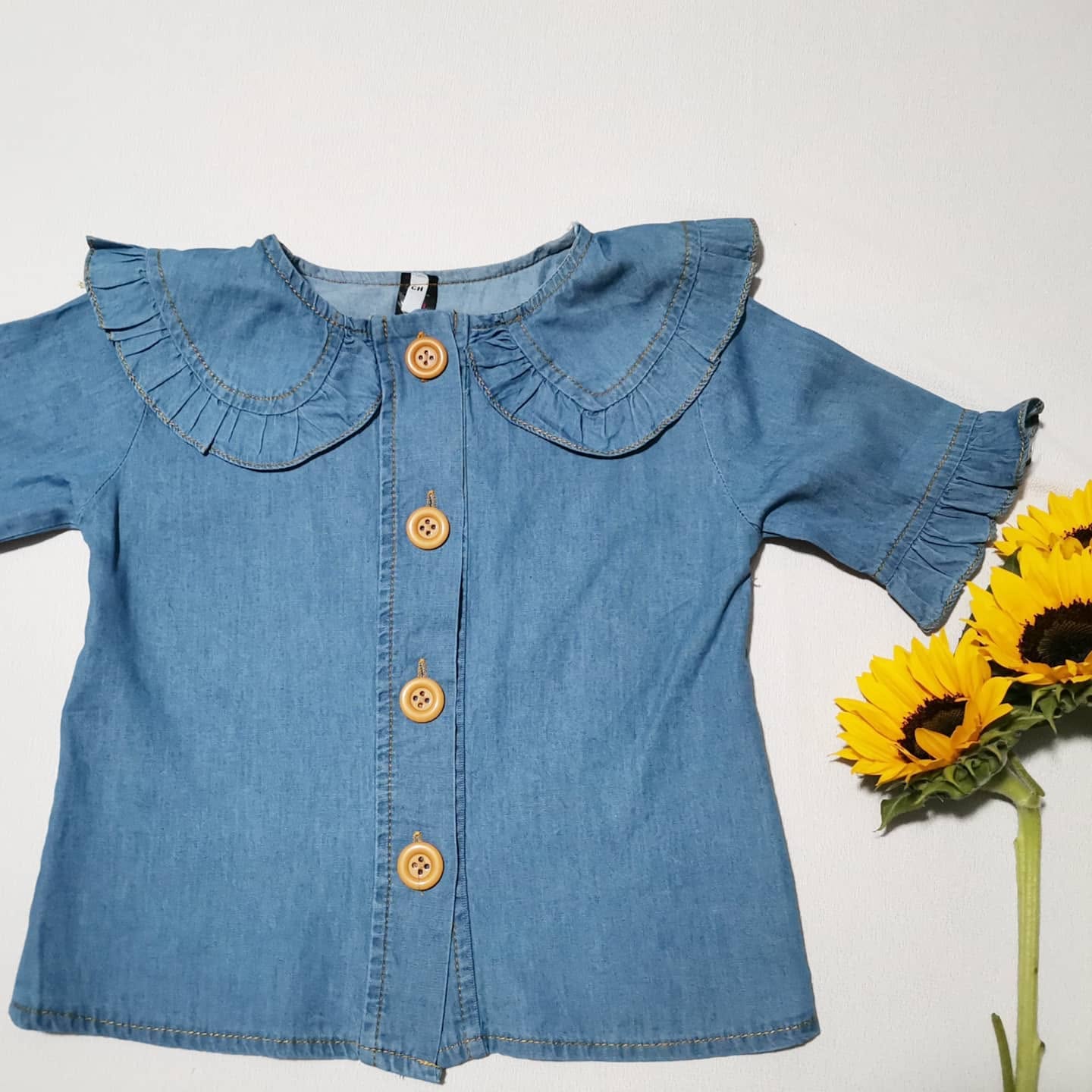 Blusa de mezclilla de niña con cuello de olán y botones de madera