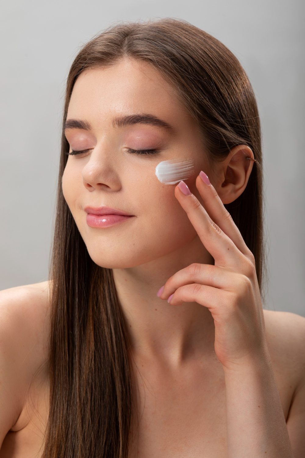 A close-up of hands applying sunscreen on the face.