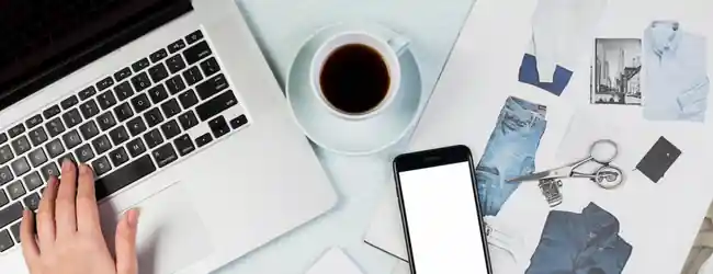 Items on a desk including coffee cup, phone, and laptop.