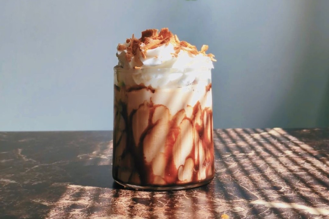 Un capricho irresistible para el alma
  Café frío con un toque de chocolate, coronado con una nube de crema batida y crujientes virutas. Perfecto para esos momentos en los que solo quieres consentirte.