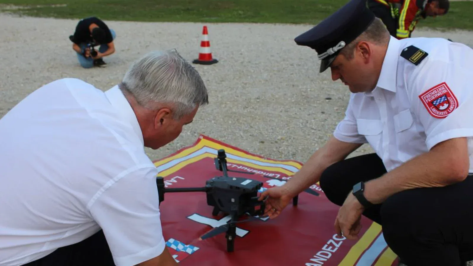 Two Landshut district fire-service officials inspect an emergency-response drone on its landing pad.