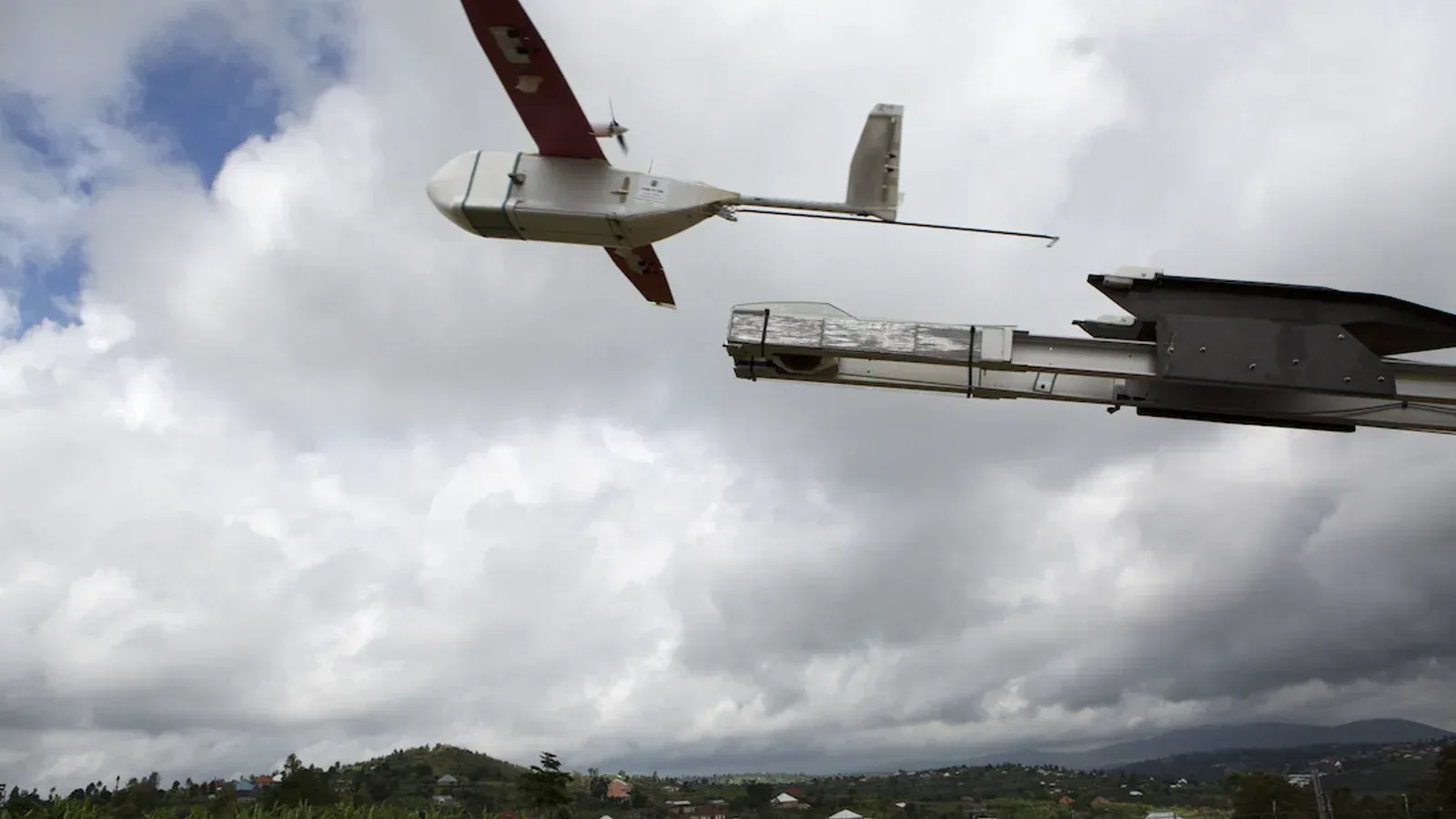 A Zipline fixed-wing medical-delivery drone launches from a powered rail in Rwanda.