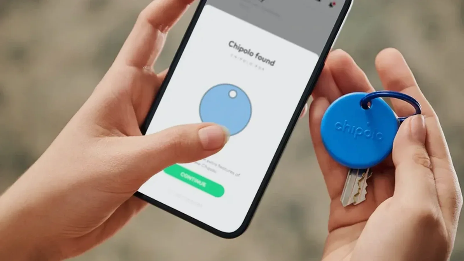 A blue Chipolo POP attached to keys beside a phone showing that the item was found.