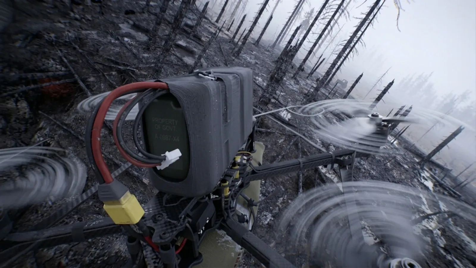 Official Bodycam promotional screenshot showing a wired electronic device in a burned forest.