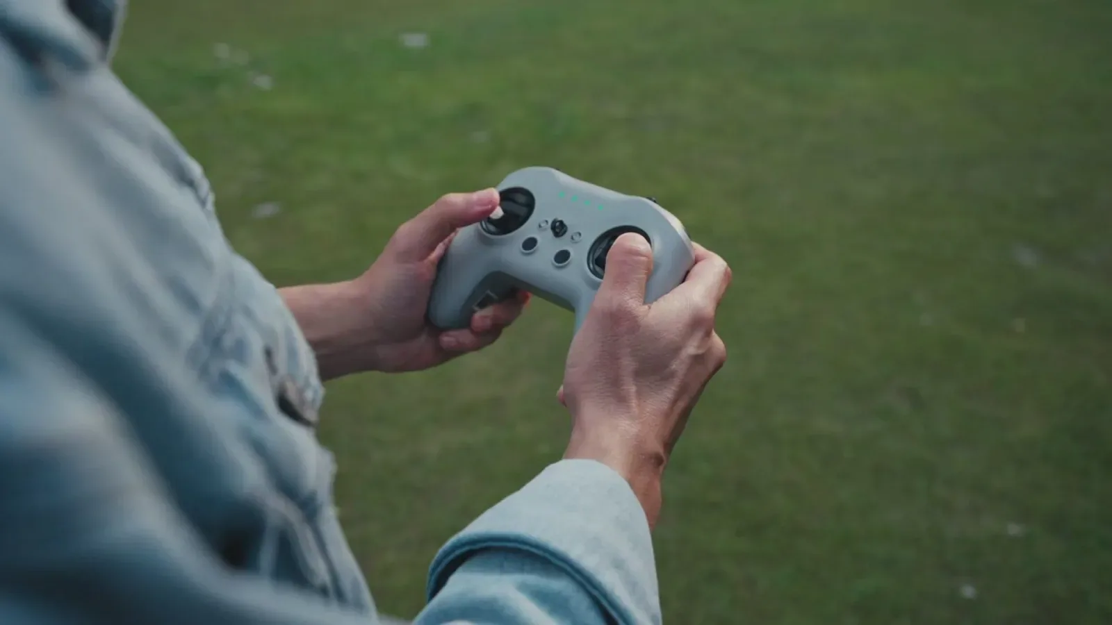 Manufacturer demonstration still showing a person holding the Eagle X dual-stick controller outdoors.