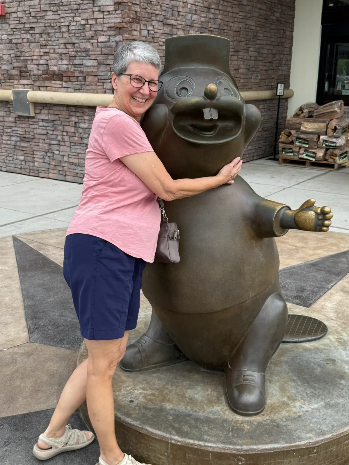 Colin's mom laughing as she hugs the Buc-ee's beaver statue during a tourist stop.