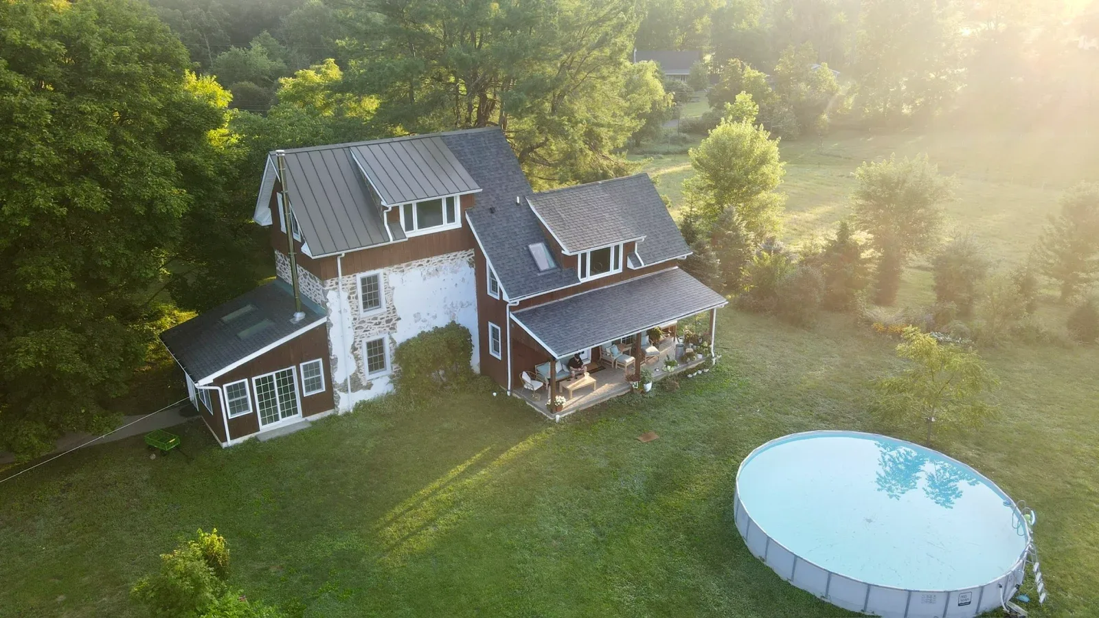 A golden-hour drone view of the farmhouse and surrounding green property in Upper Black Eddy, Pennsylvania.