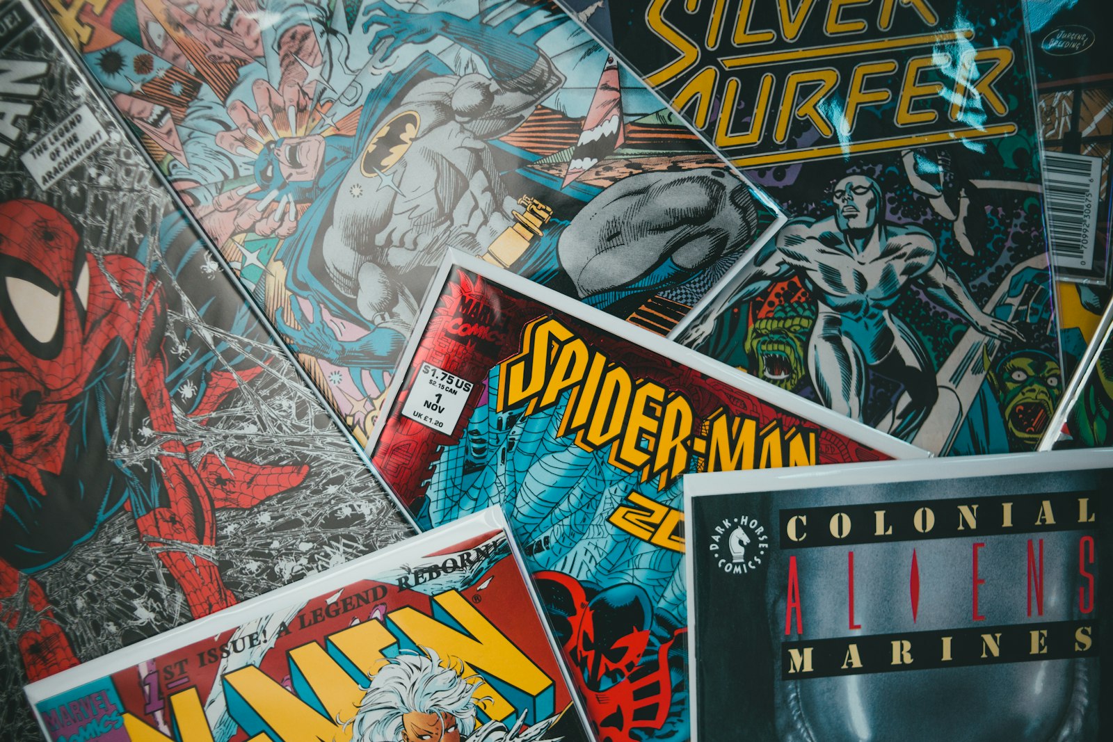 Stacks of bagged comic books on a table, covers facing up