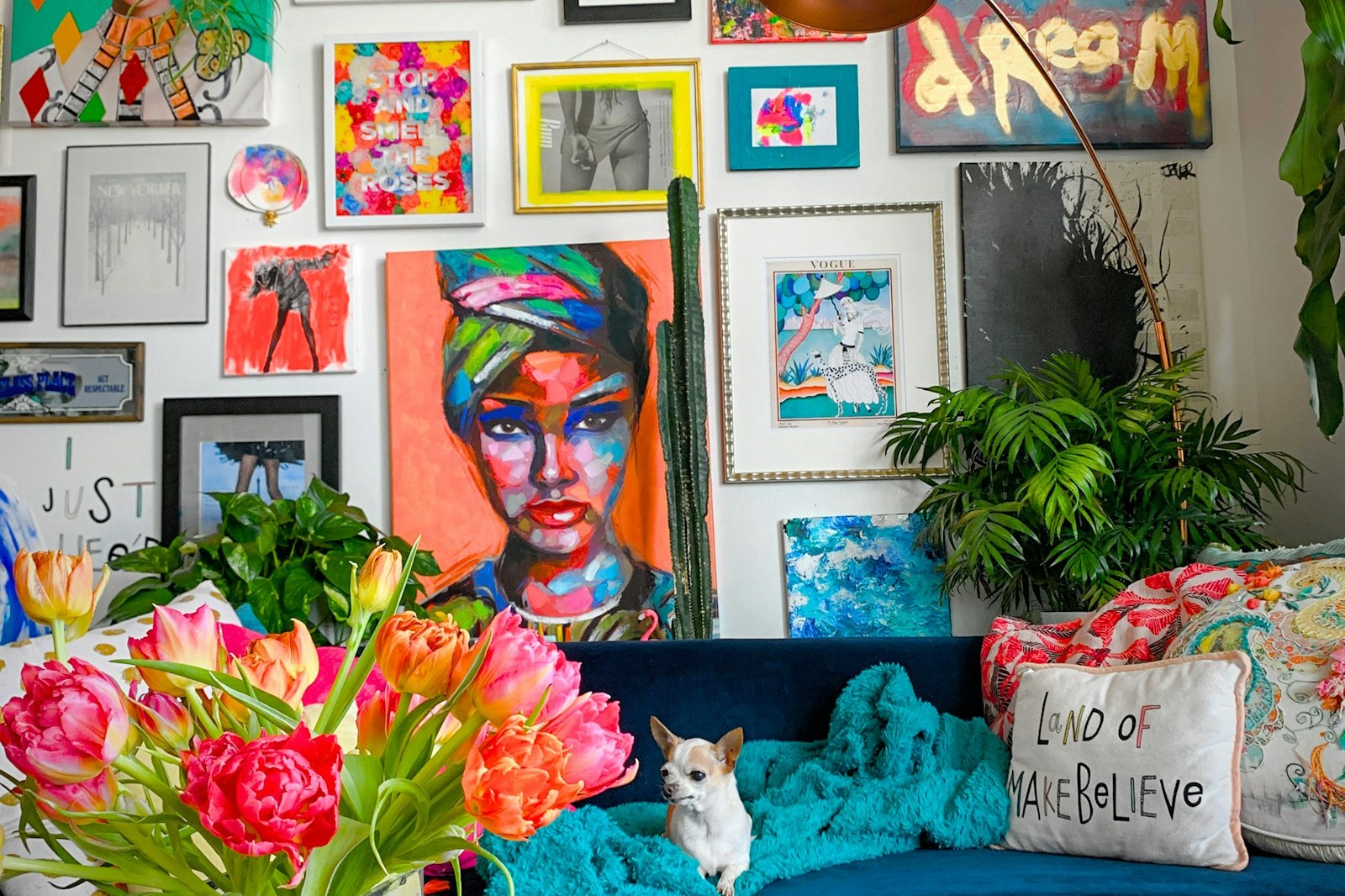 A colorful gallery wall of framed art and prints above a blue sofa