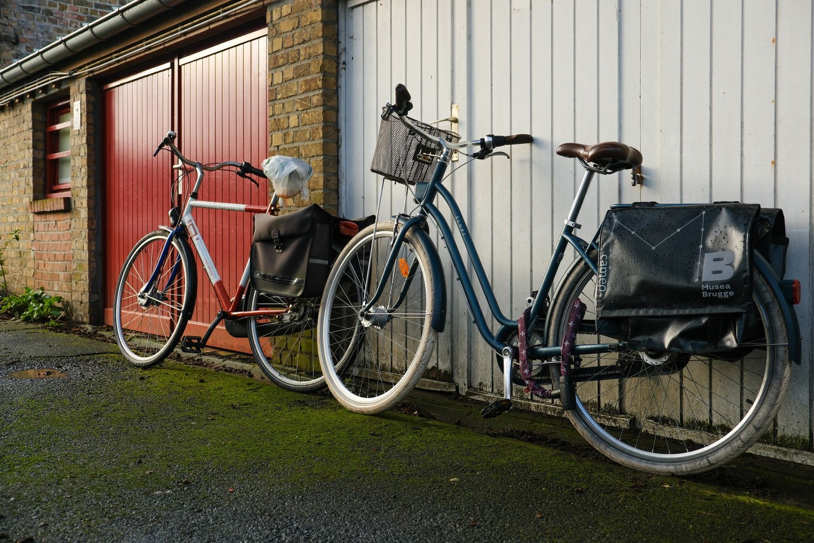 To cykler parkeret op ad en hvid garagevæg med en hjelm på styret