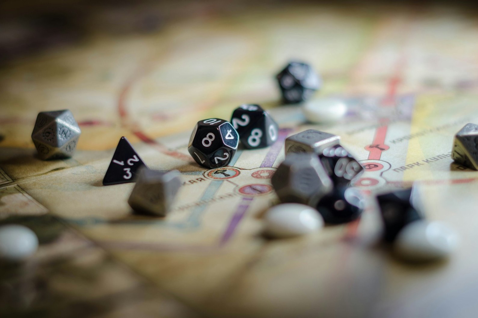 Black, silver and white polyhedral dice scattered on a paper game map