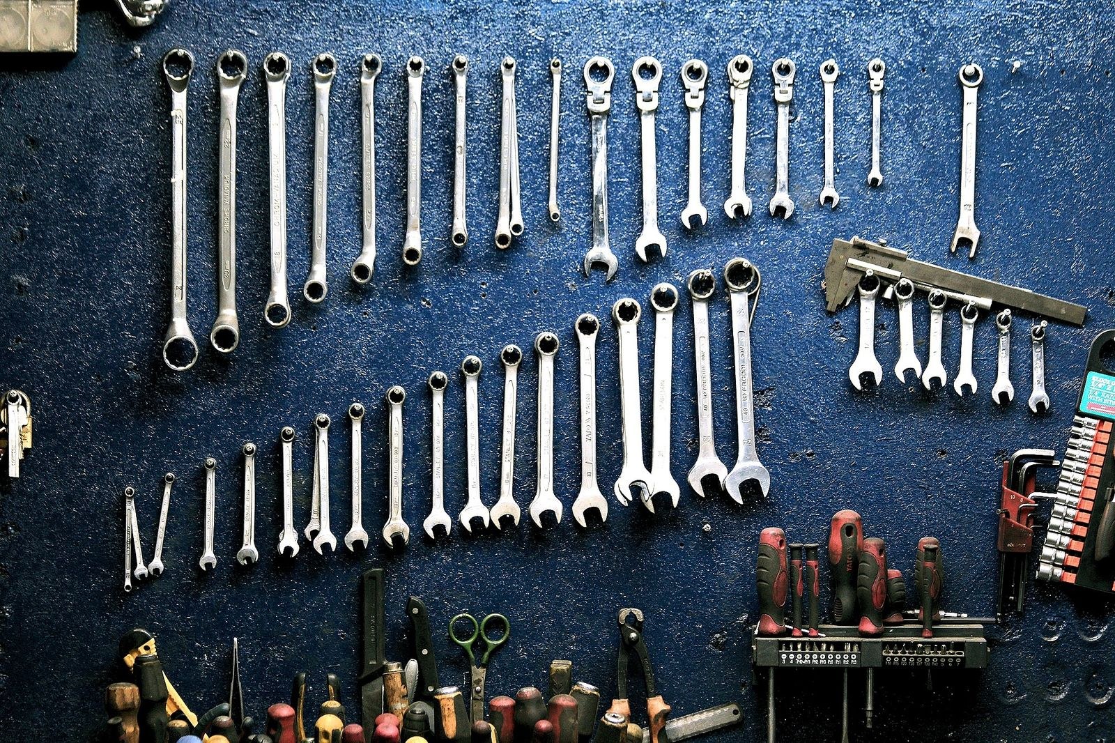 Hand tools and wrenches arranged on a dark workshop tool wall