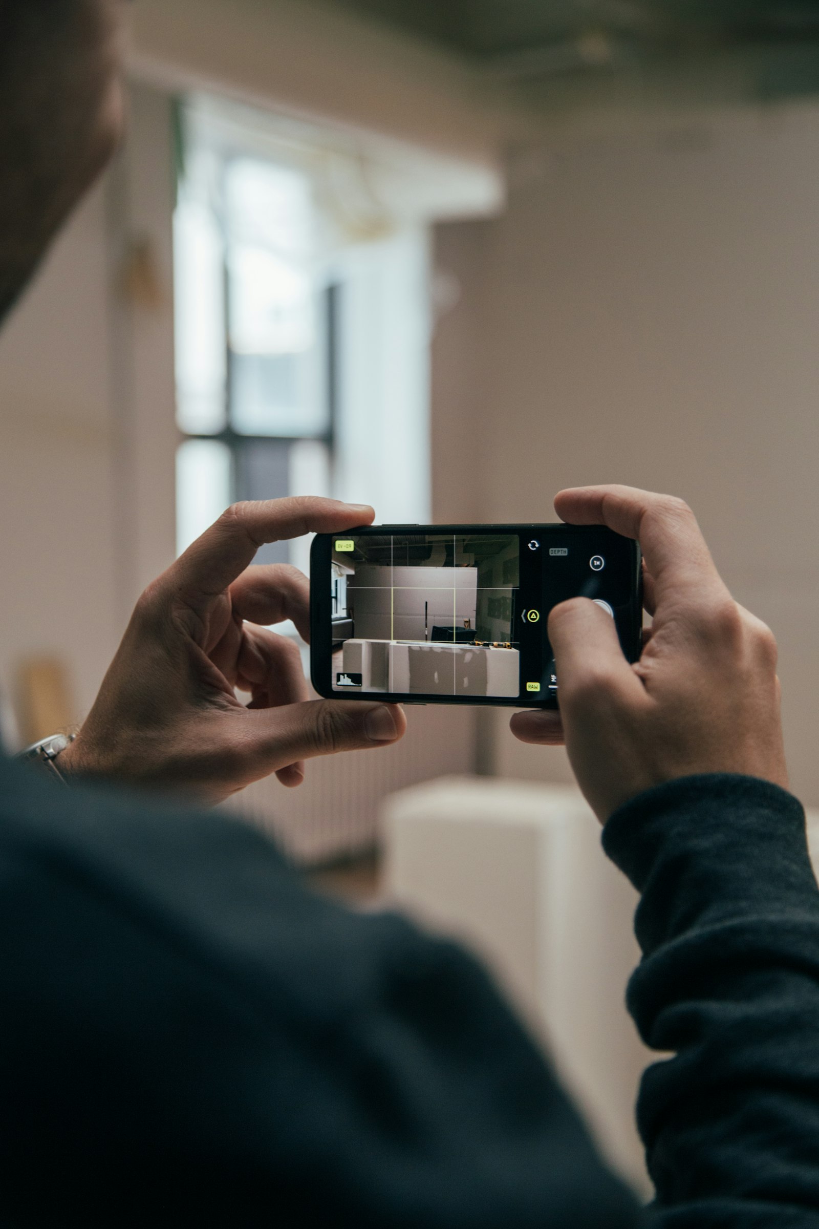 Two hands steadying a smartphone while photographing a room at home